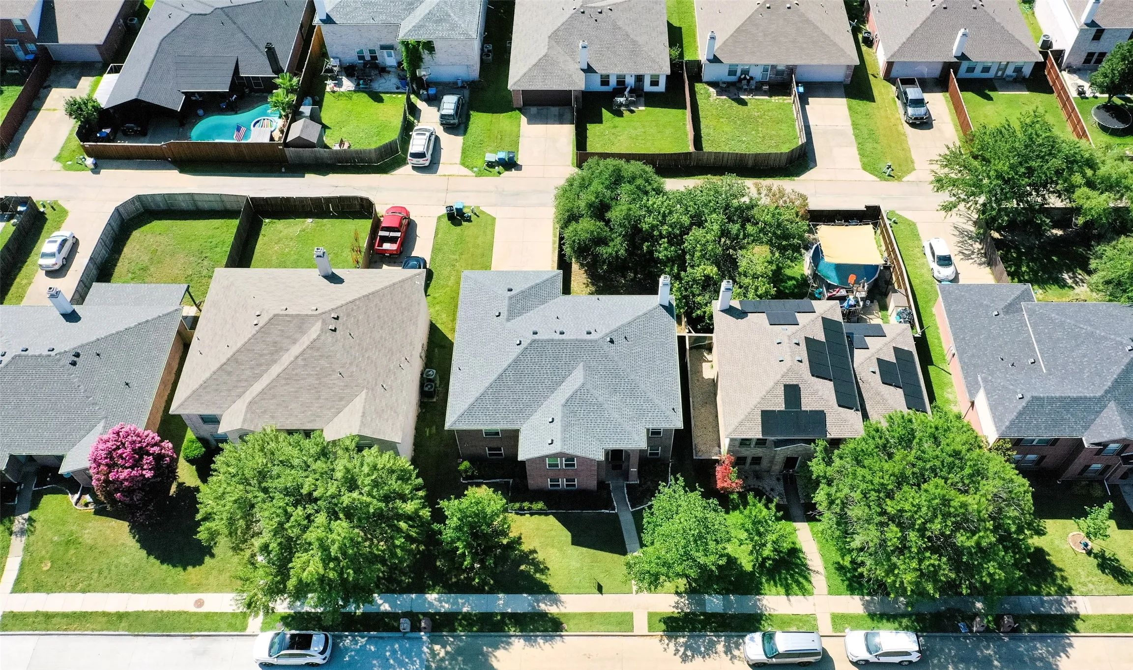 Aerial perspective showcasing a residential property with a shingle roof and mature trees surrounding the perimeter