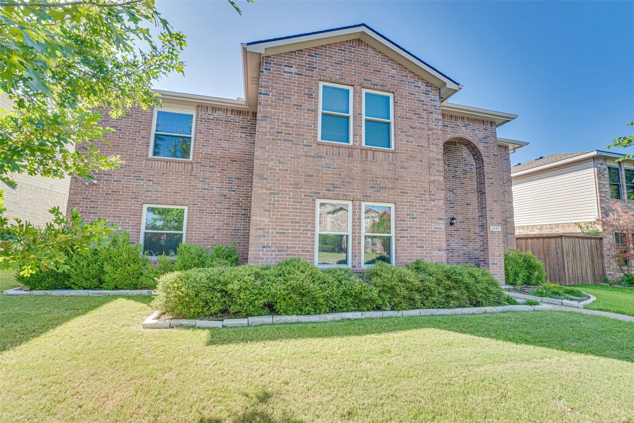 Brick two-story exterior featuring a prominent arched entryway