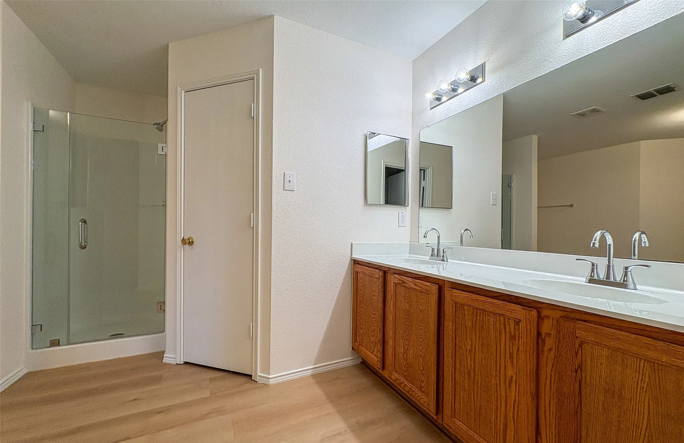 Bathroom featuring a dual vanity with wood cabinetry, light-toned countertops, and a full-width mirror