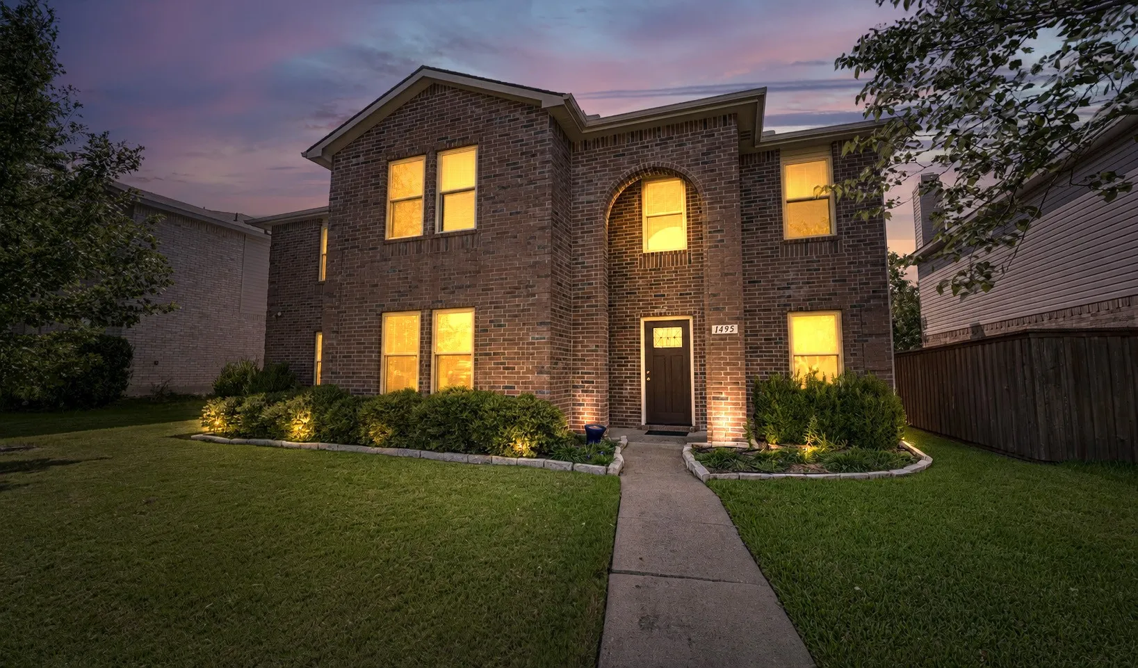 Brick-clad two-story residence featuring a prominent arched entryway and a dark front door