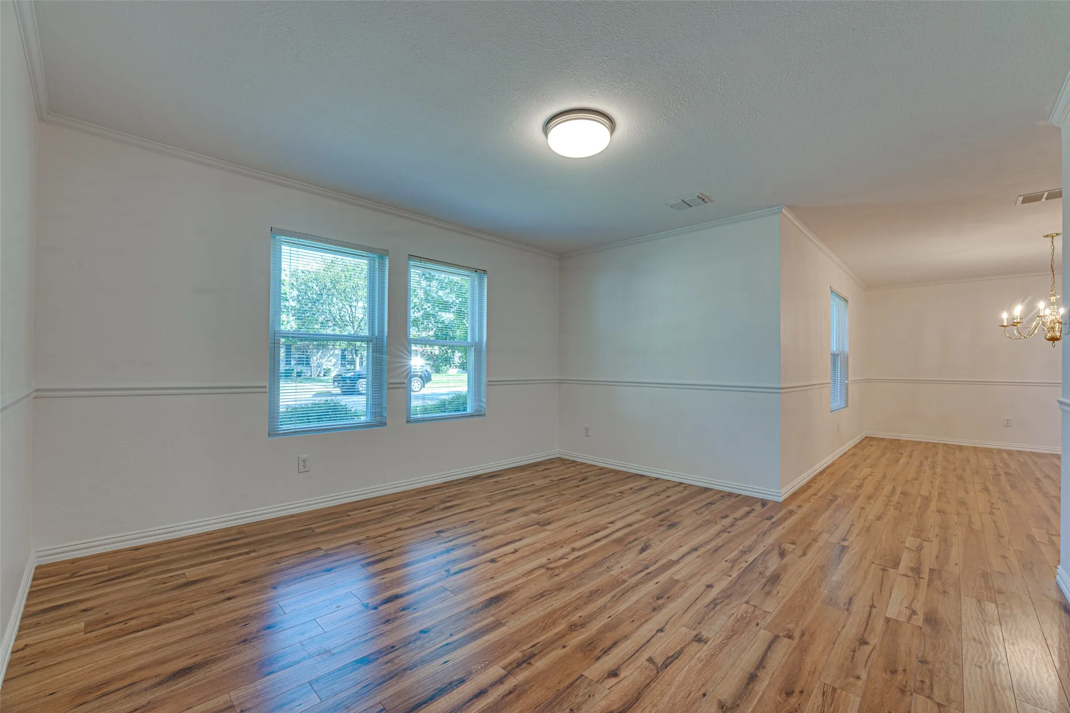 Open concept interior featuring wood-finish flooring, white walls with chair rail molding, and crown molding