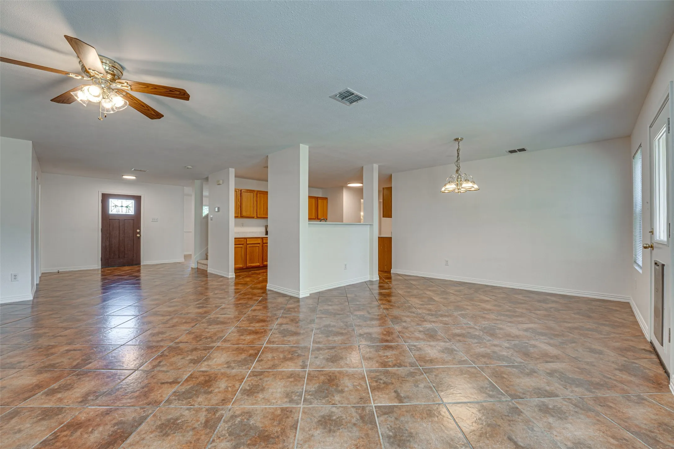 Spacious interior featuring large format tile flooring, white walls, and a ceiling fan with light fixture