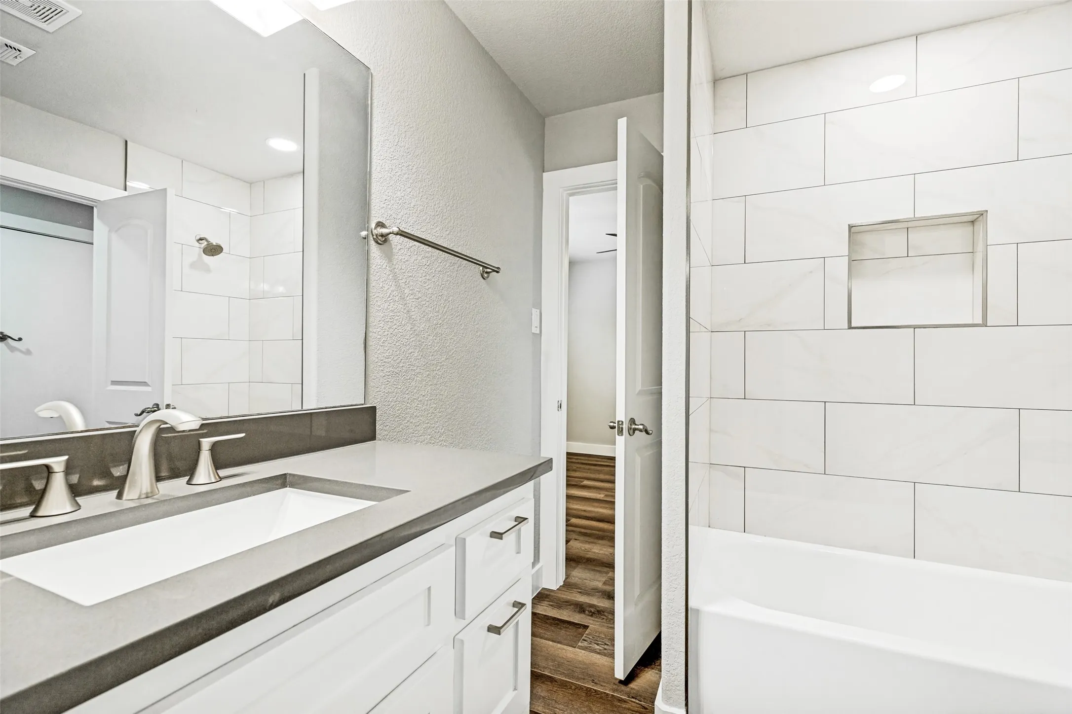 Bathroom featuring a white vanity with a gray countertop, an undermount sink, and brushed nickel fixtures