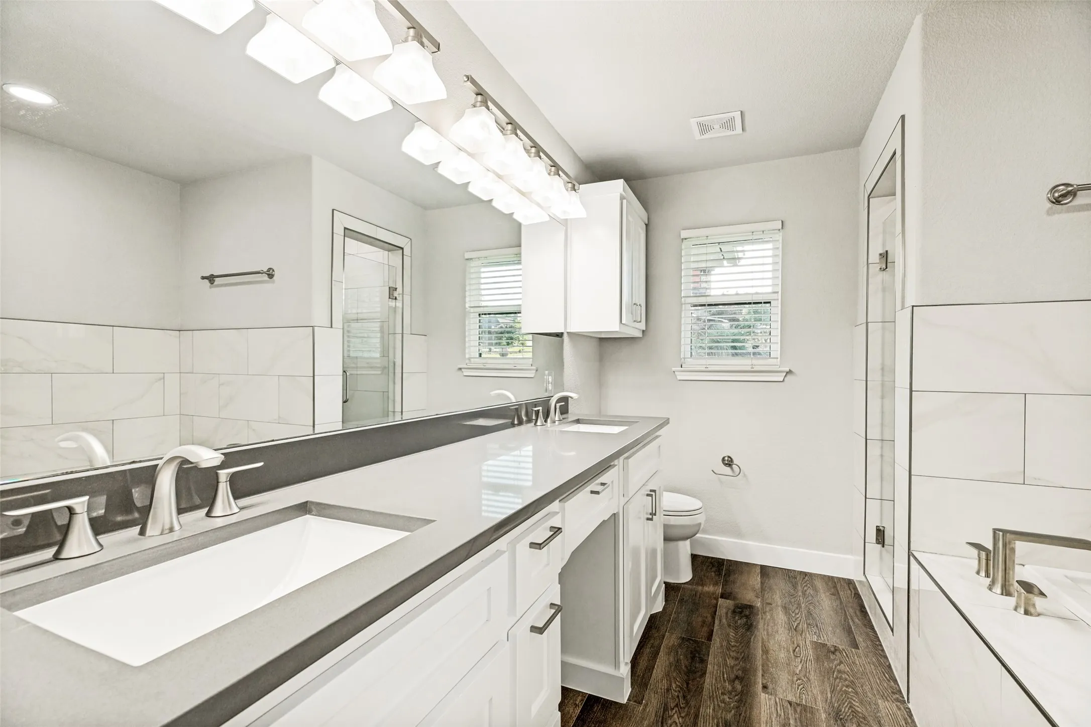 Double vanity with undermount sinks, stone countertop, and brushed nickel fixtures