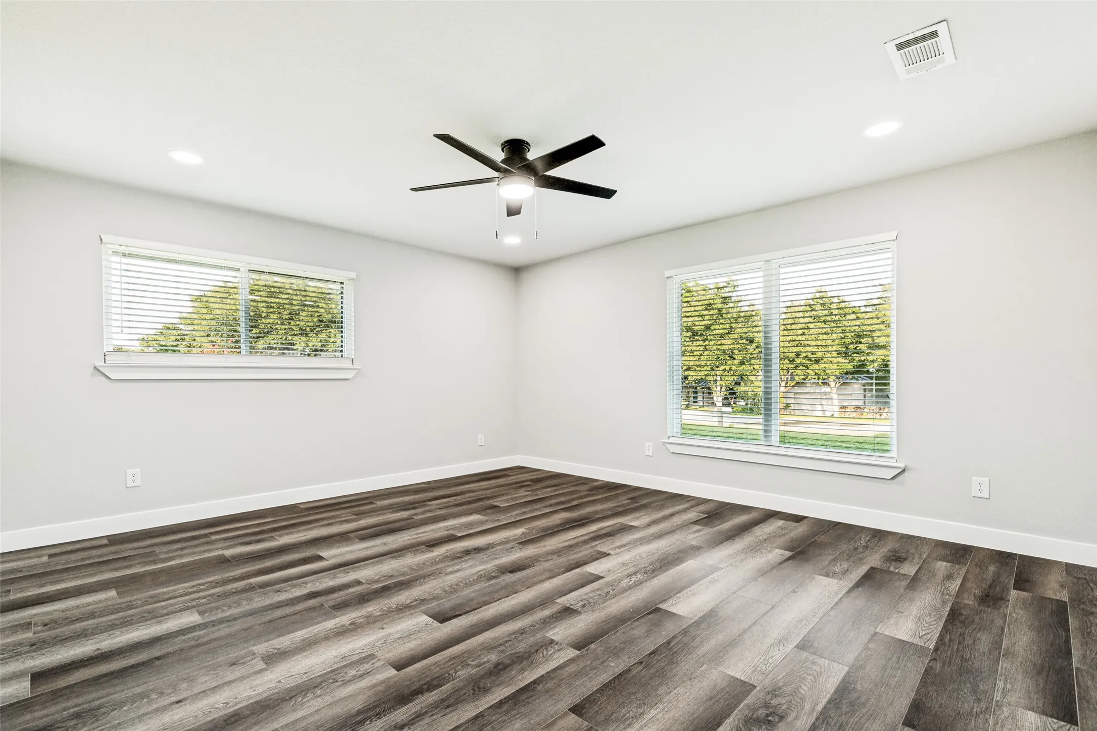 Spacious room featuring wood-finish flooring, light gray walls, and white trim