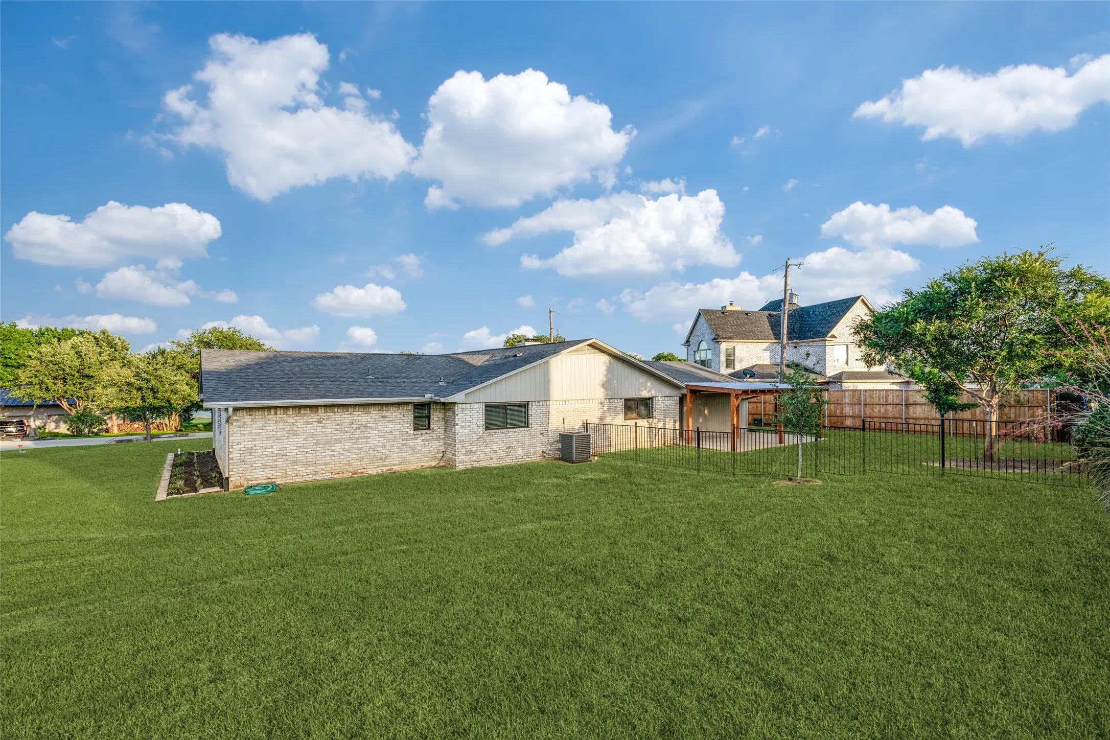 Expansive green lawn surrounds the property, featuring a light brick and siding exterior