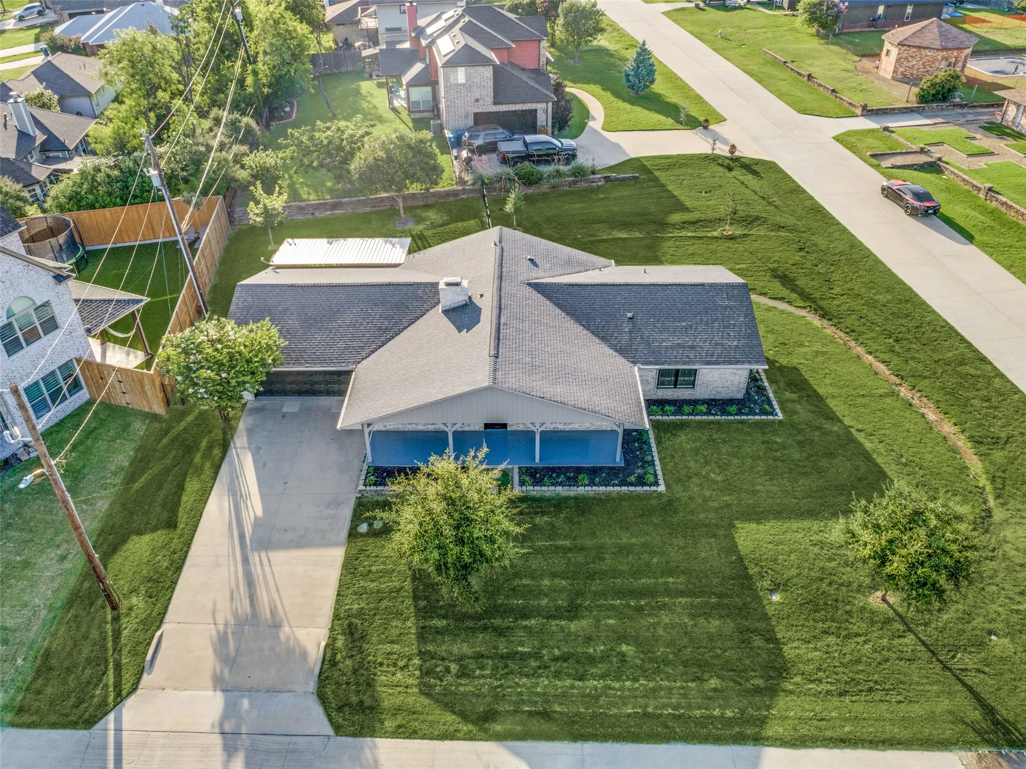 Single-story residence featuring a covered front porch with blue-painted floor, a spacious driveway, and a shingle roof