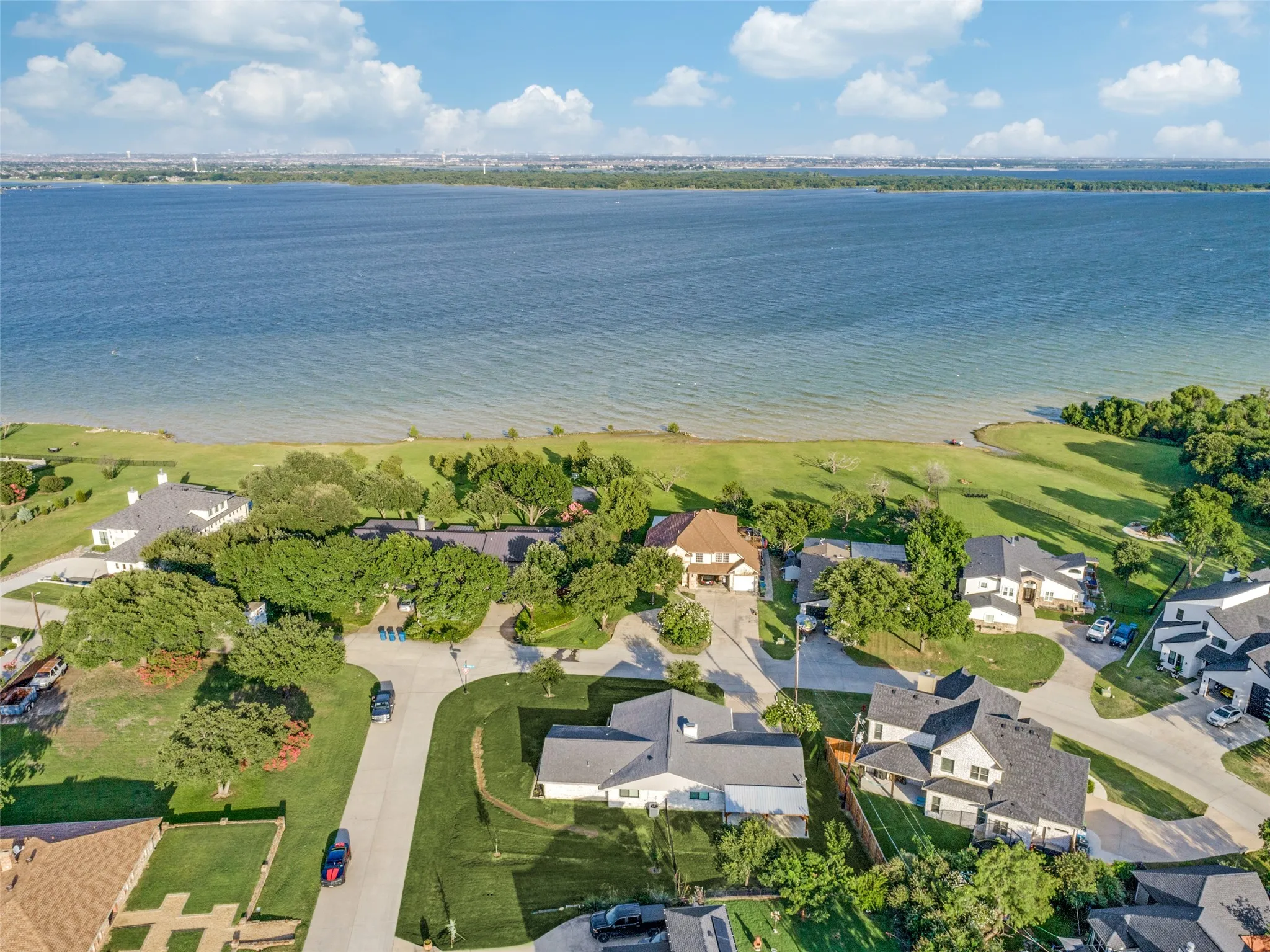 Waterfront property featuring a large body of water, extensive green space, and mature trees