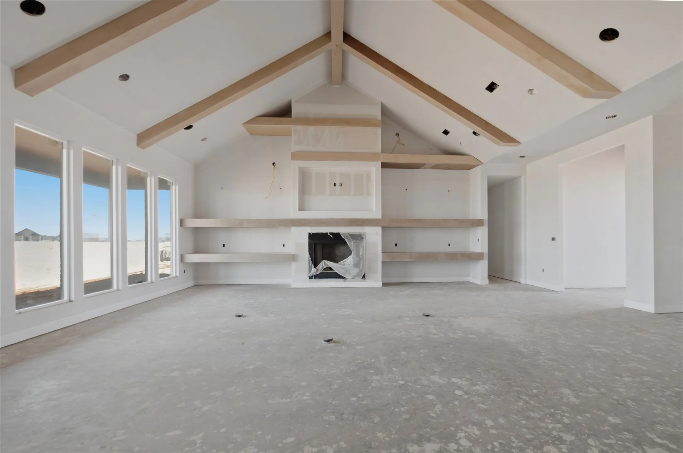 Vaulted cleiling with exposed wood beams, fireplace with integrated shelving, recessed lighting, and multiple vertical windows