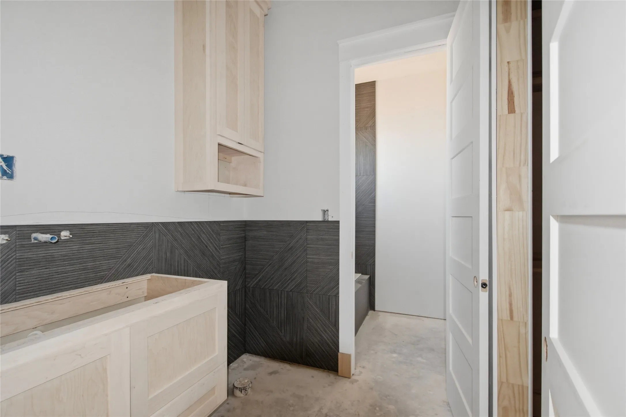 Unfinished wood cabinetry paired with a distinctive dark tile backsplash featuring a geometric pattern