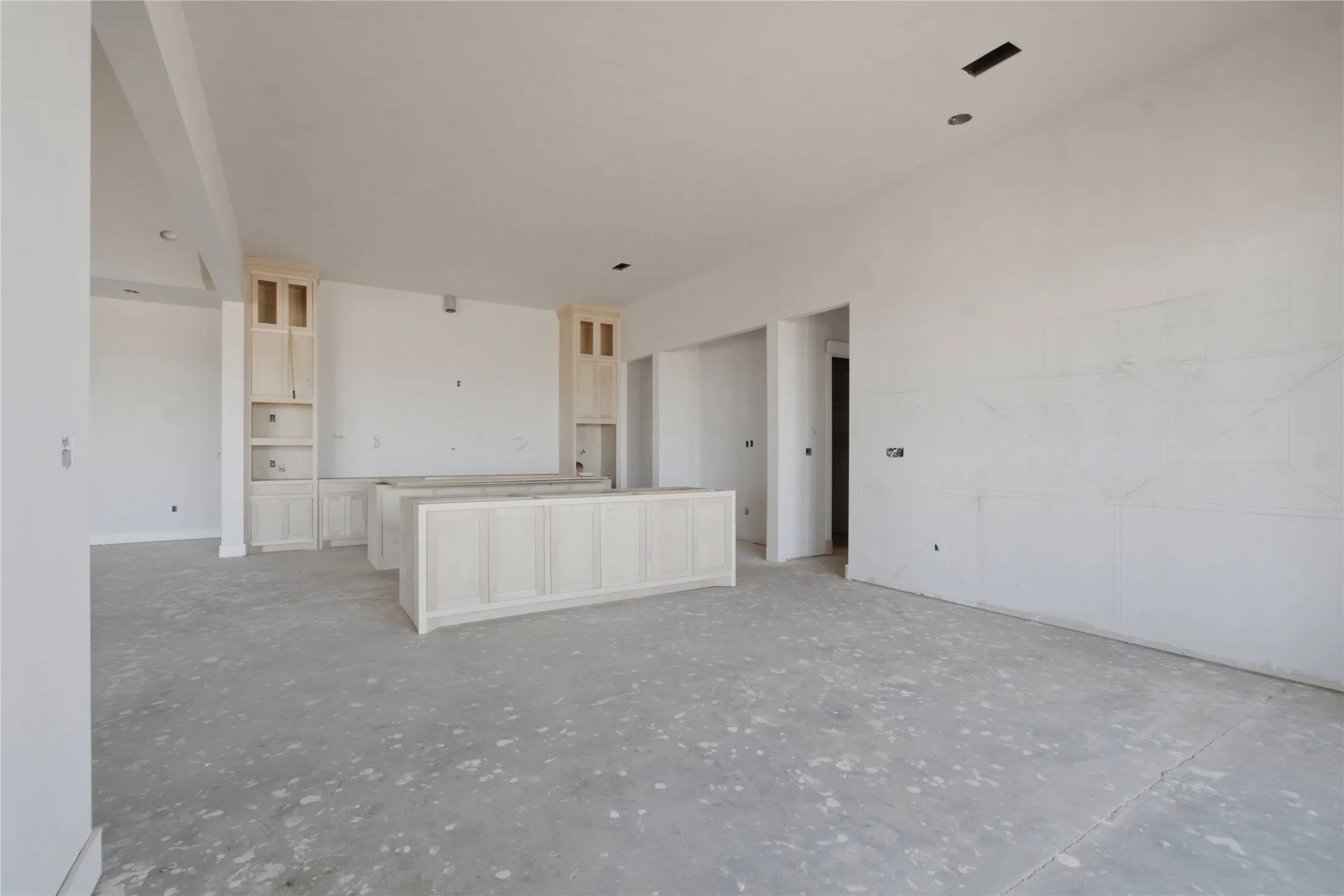 Spacious open-concept area featuring two light wood-finish kitchen islands with panel detailing