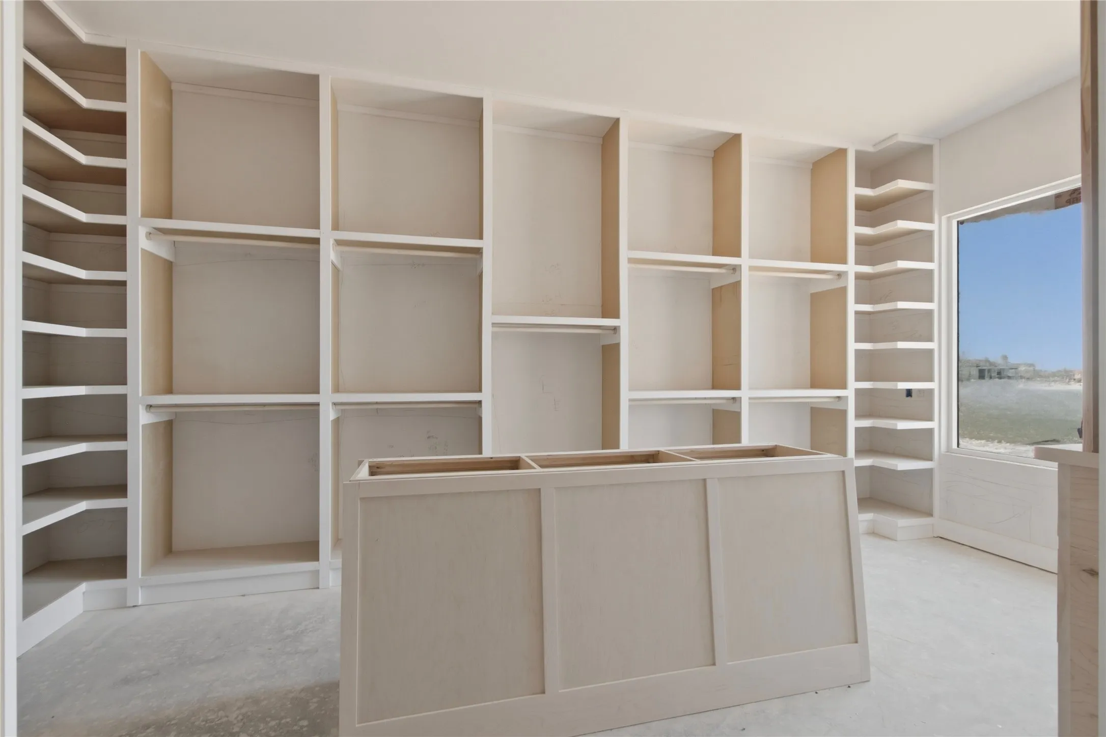 Spacious custom closet featuring extensive built-in shelving, integrated hanging rods, corner shelving, and a central island base