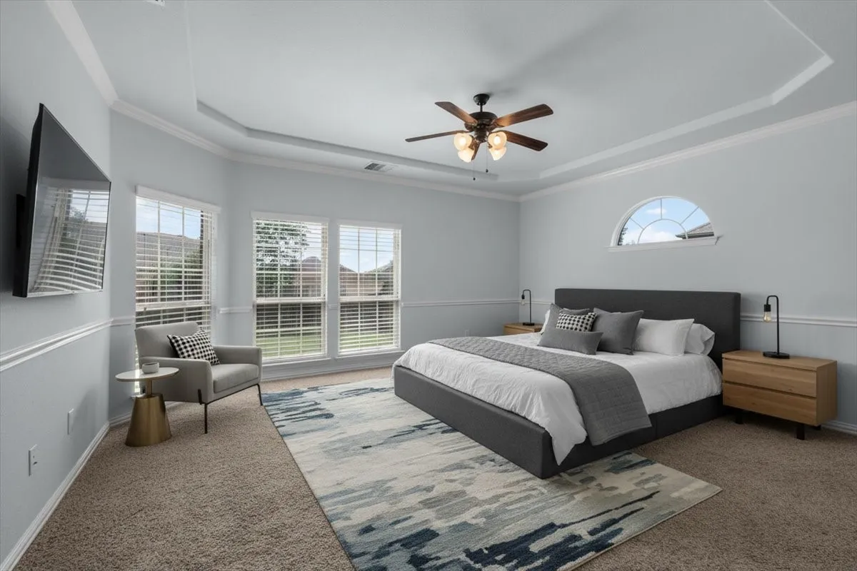 Carpeted bedroom featuring a tray ceiling and a half-moon window. **This image has been virtually staged.**
