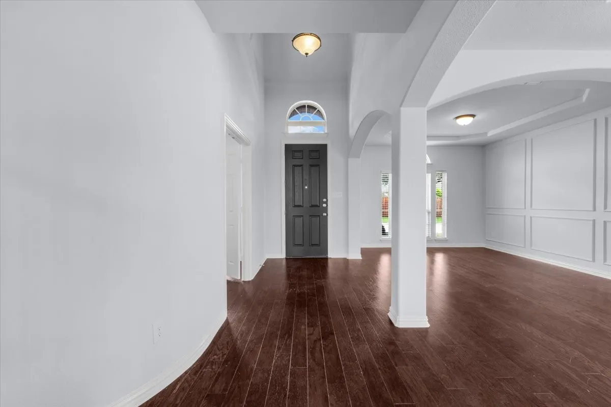 Entryway featuring dark wood-finish flooring, with an arched
