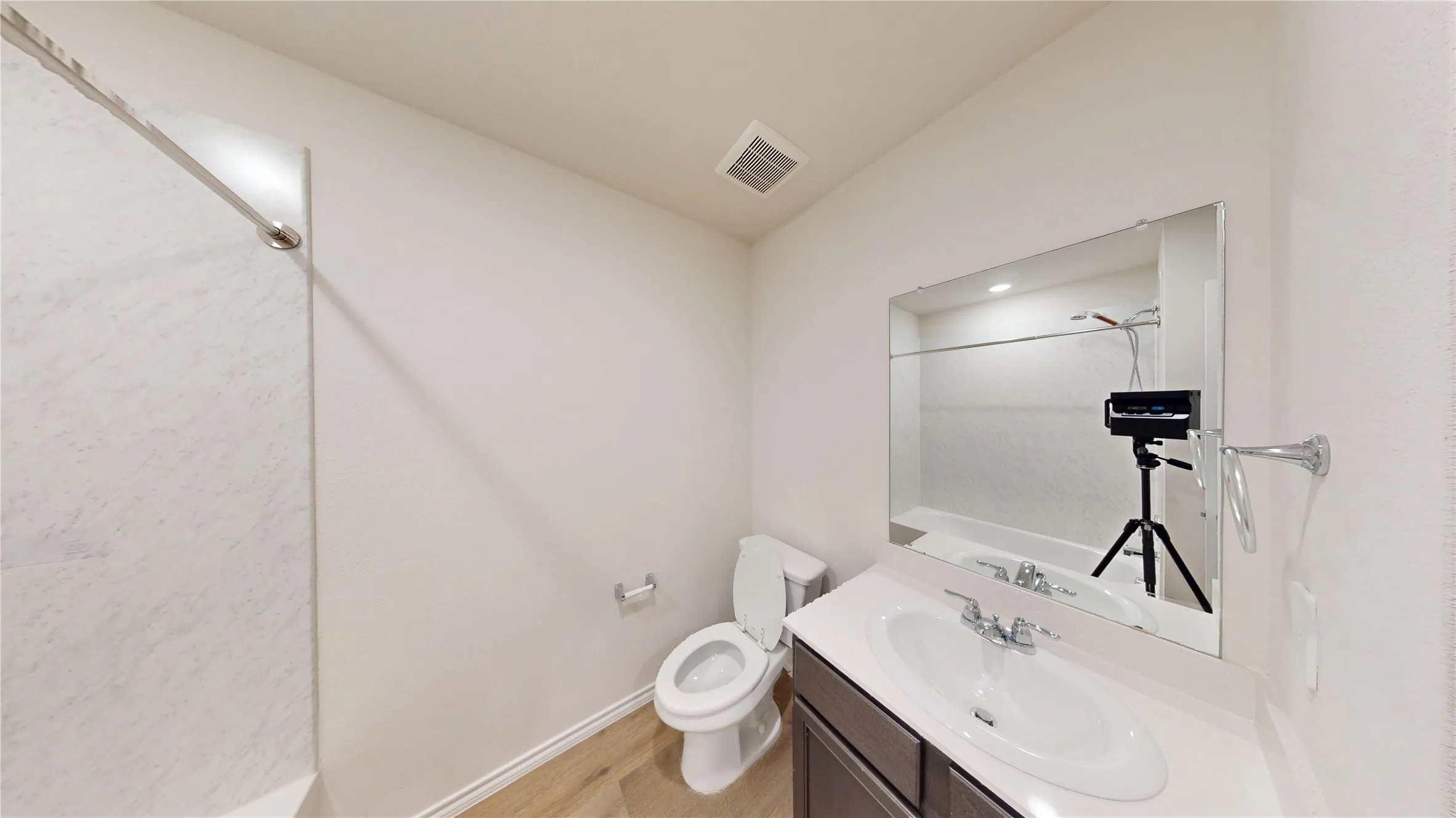 Shower with white subway tile surround, single vanity with integrated sink, dark wood-finish cabinetry, and framed mirror