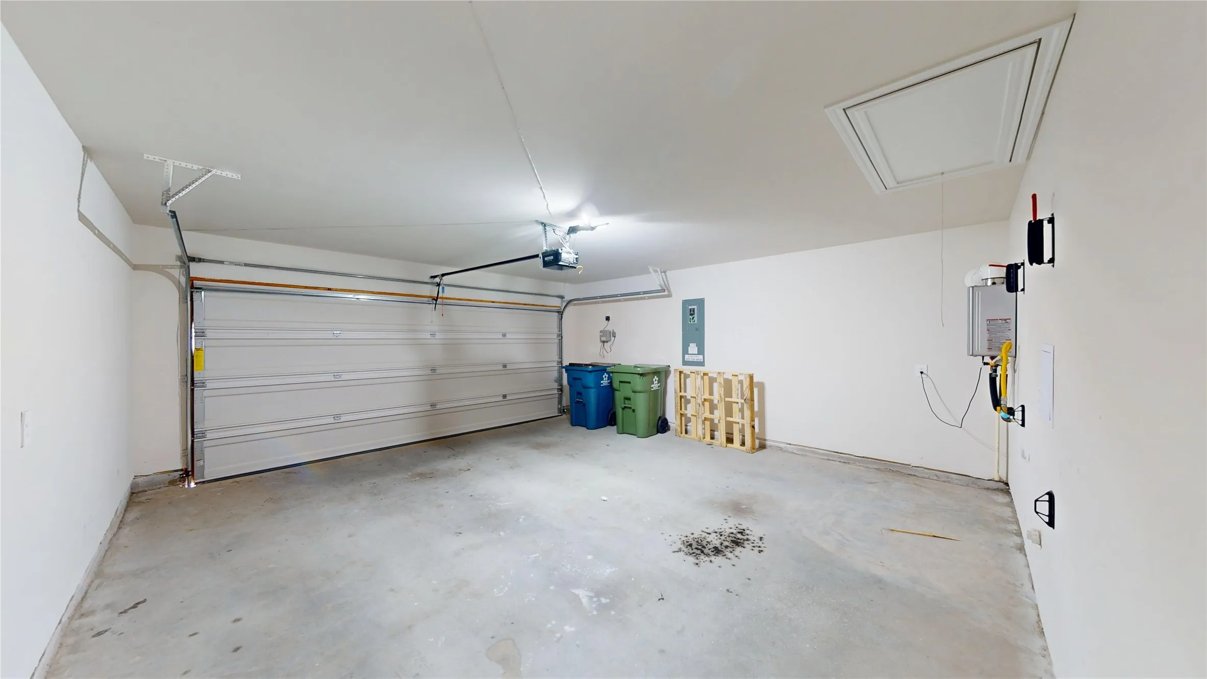 Two-car garage with a roll-up door, concrete flooring, and an overhead lighting fixture