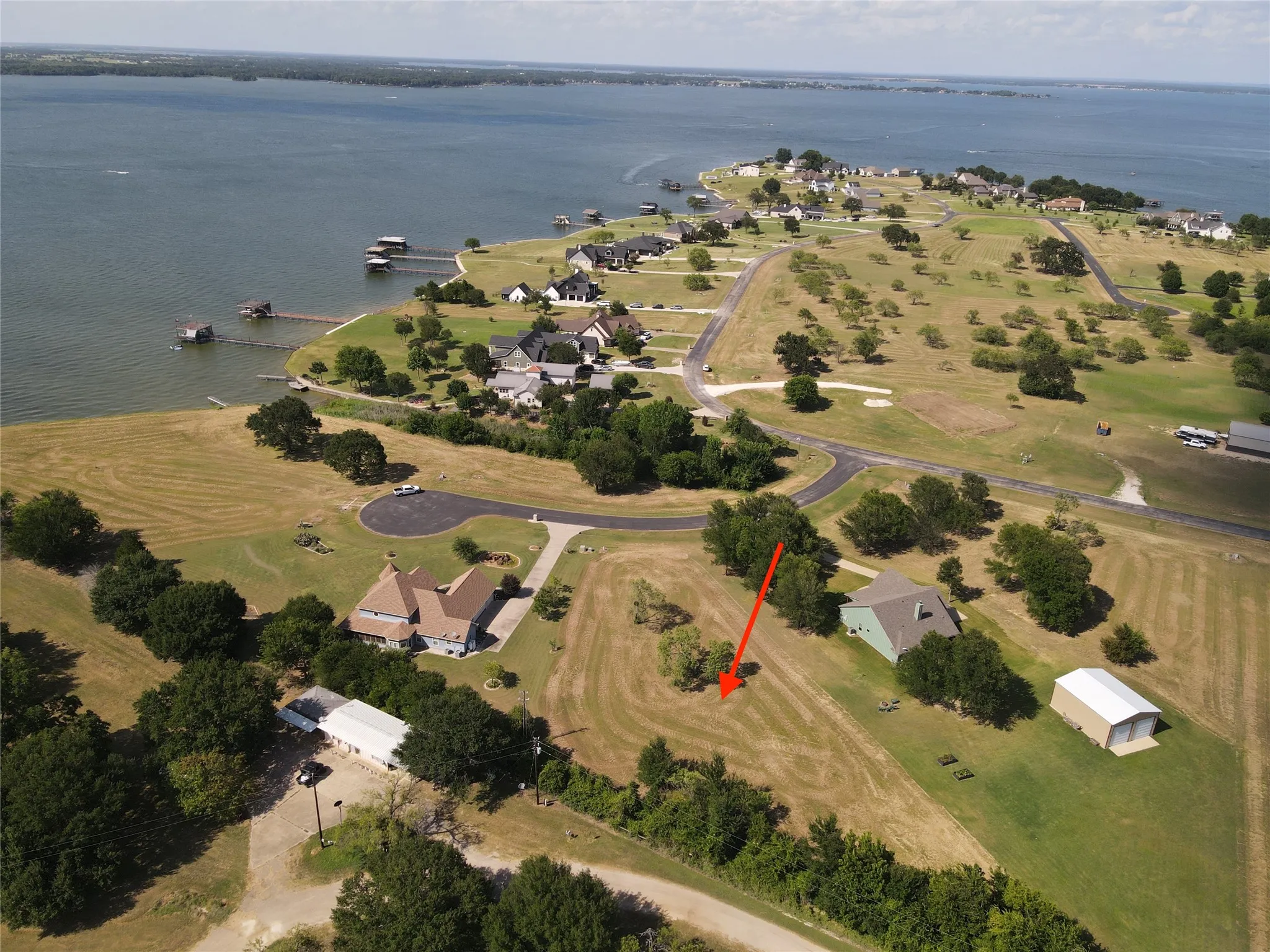 Expansive lakeside property featuring a large body of water, green lawns, and scattered mature trees