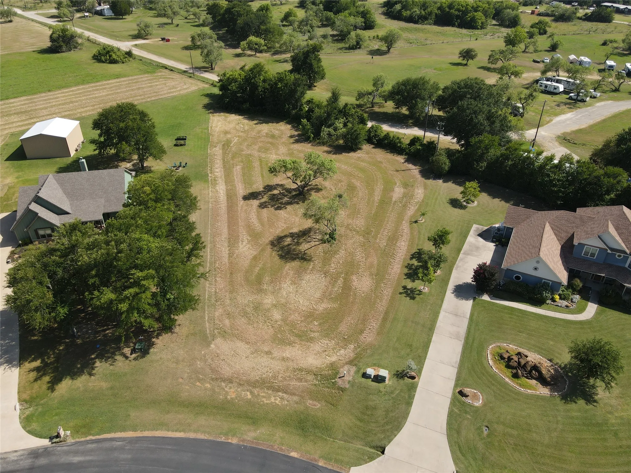 Expansive land parcel featuring existing trees, a level terrain, and proximity to established residential properties