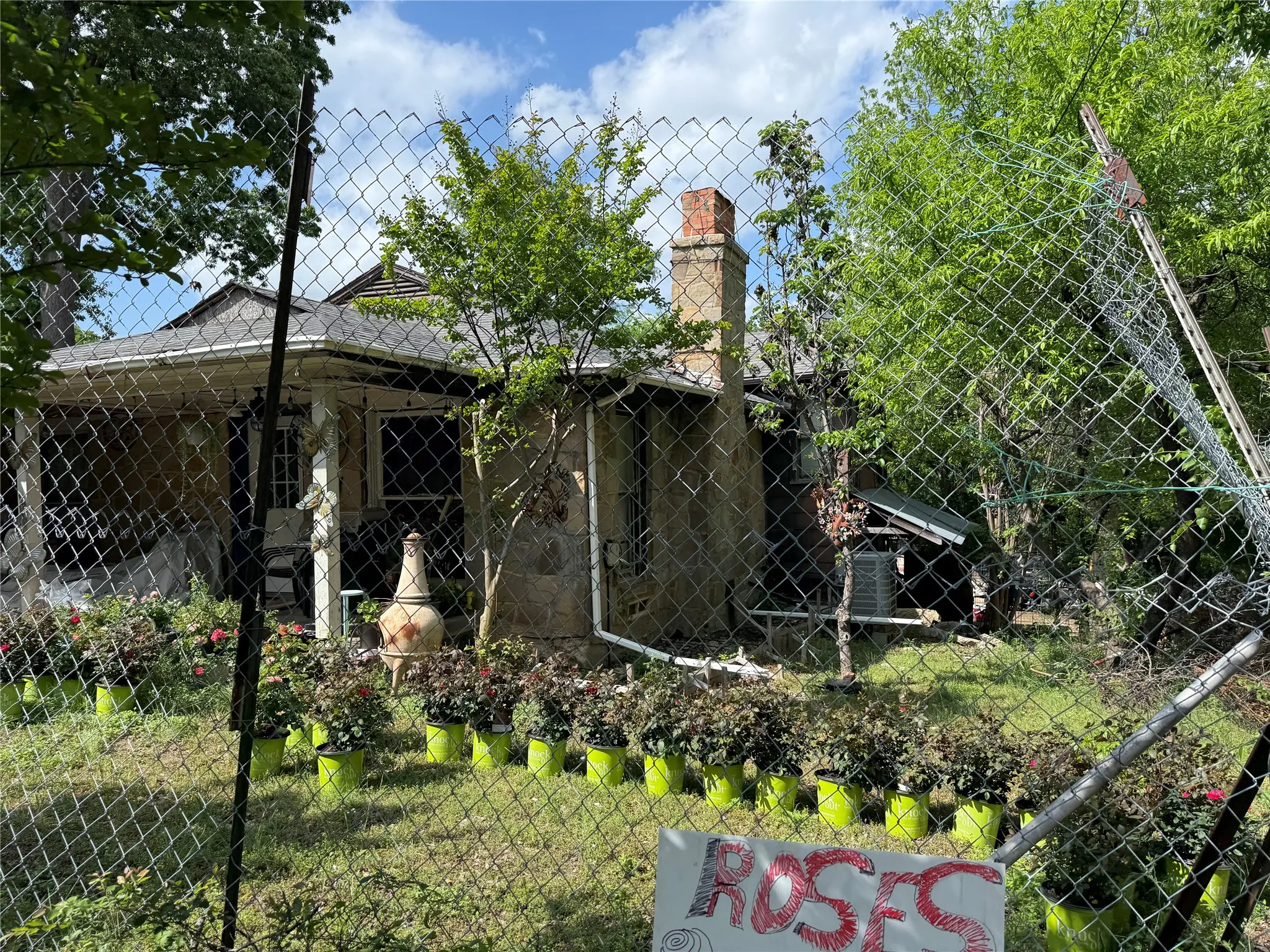 Exterior features include a chain-link fence, established trees, and a visible chimney