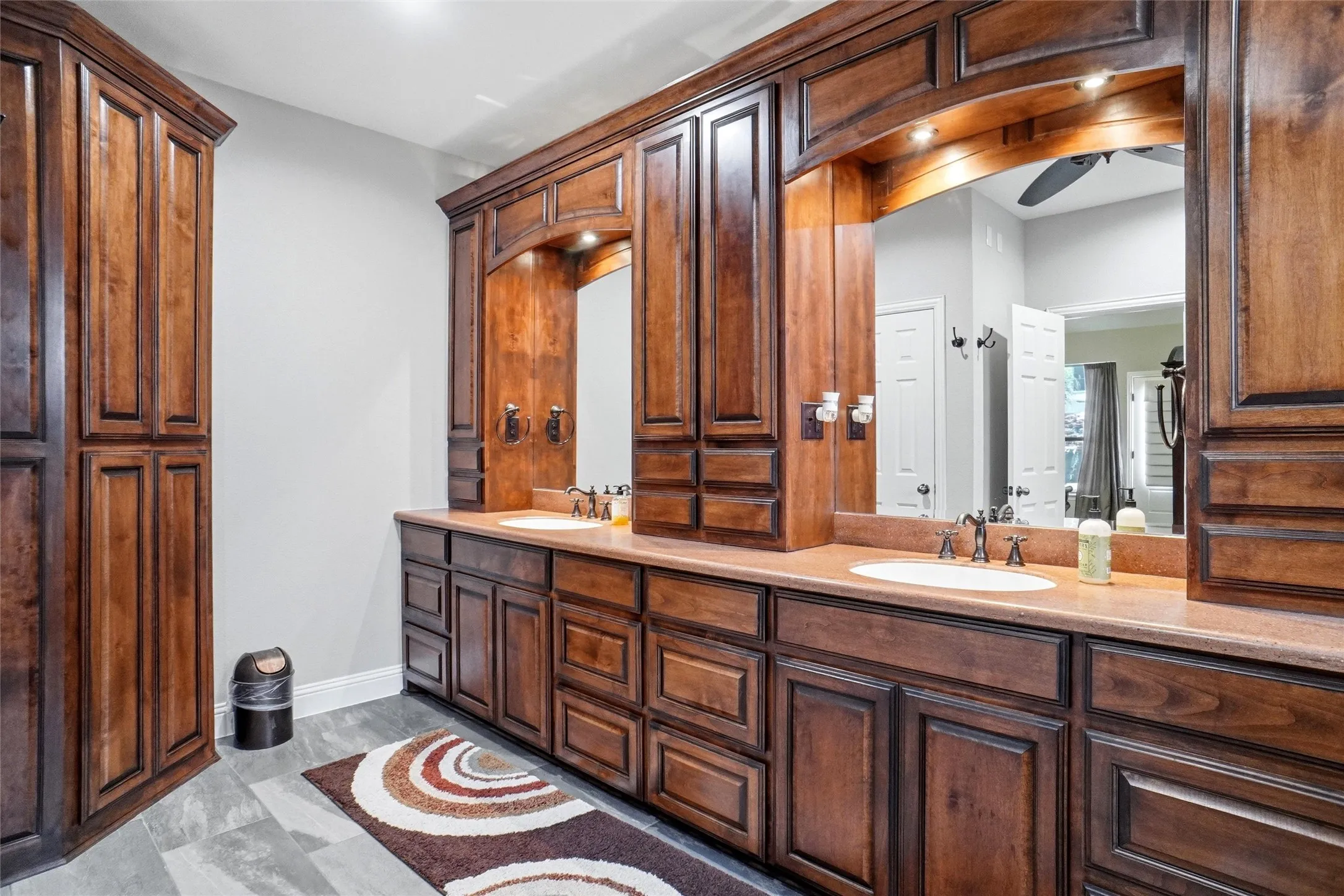 Dual vanity featuring rich wood-finish cabinetry, integrated sinks, and coordinating countertops