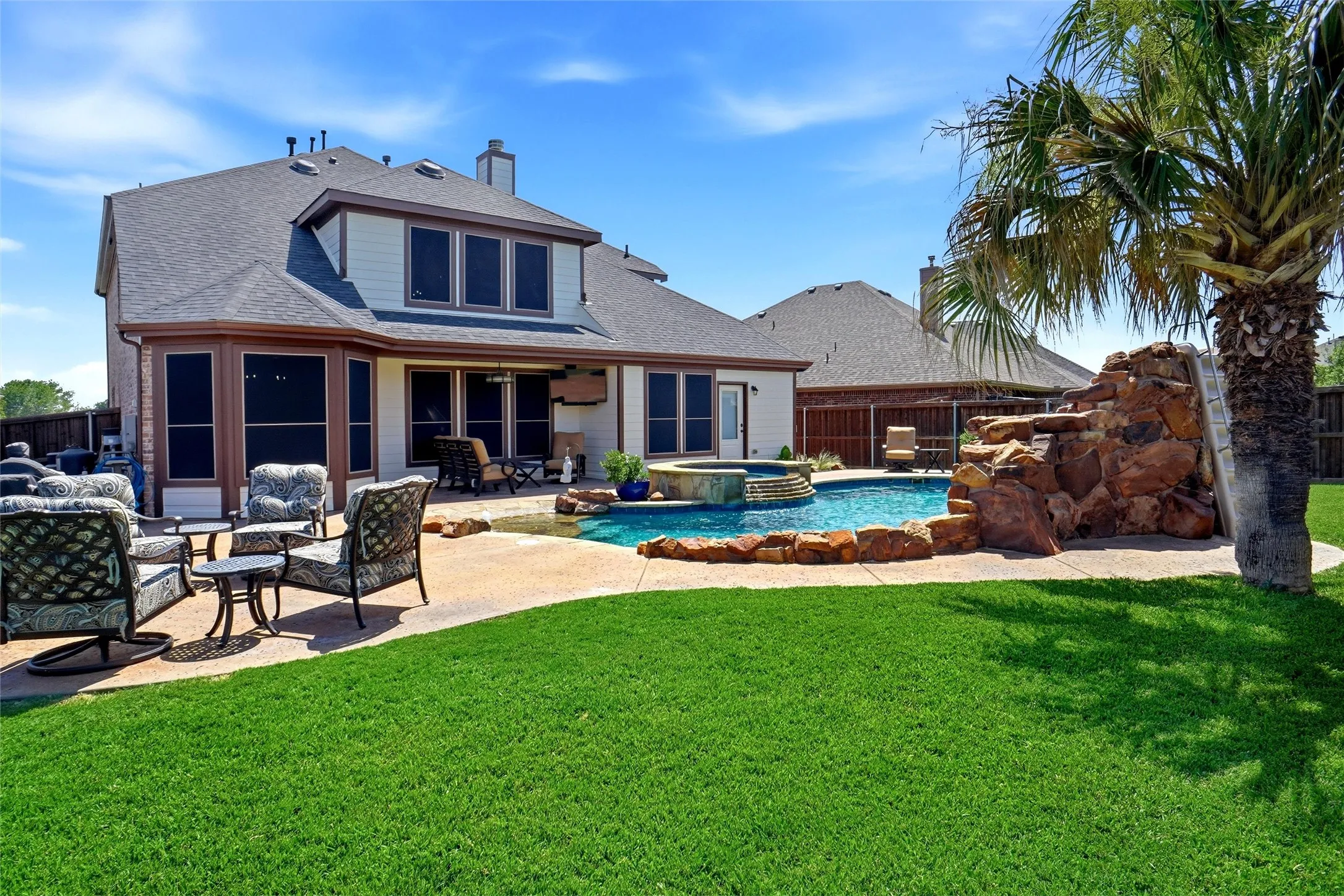 Spacious backyard featuring a large swimming pool with a rock waterfall and integrated spa
