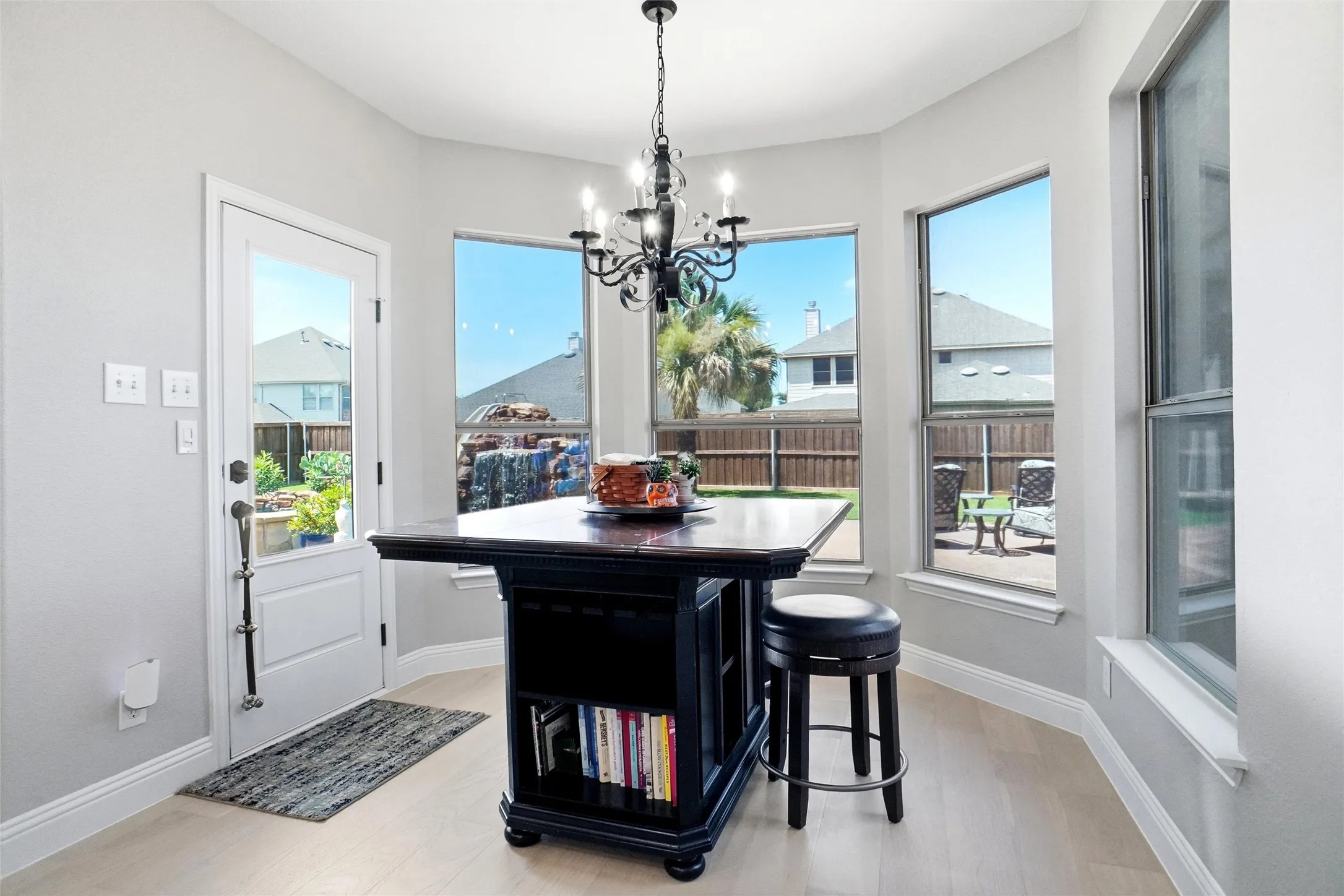 Breakfast nook featuring a multi-paned glass-insert door, bay windows, wood-finish flooring, and a black chandelier