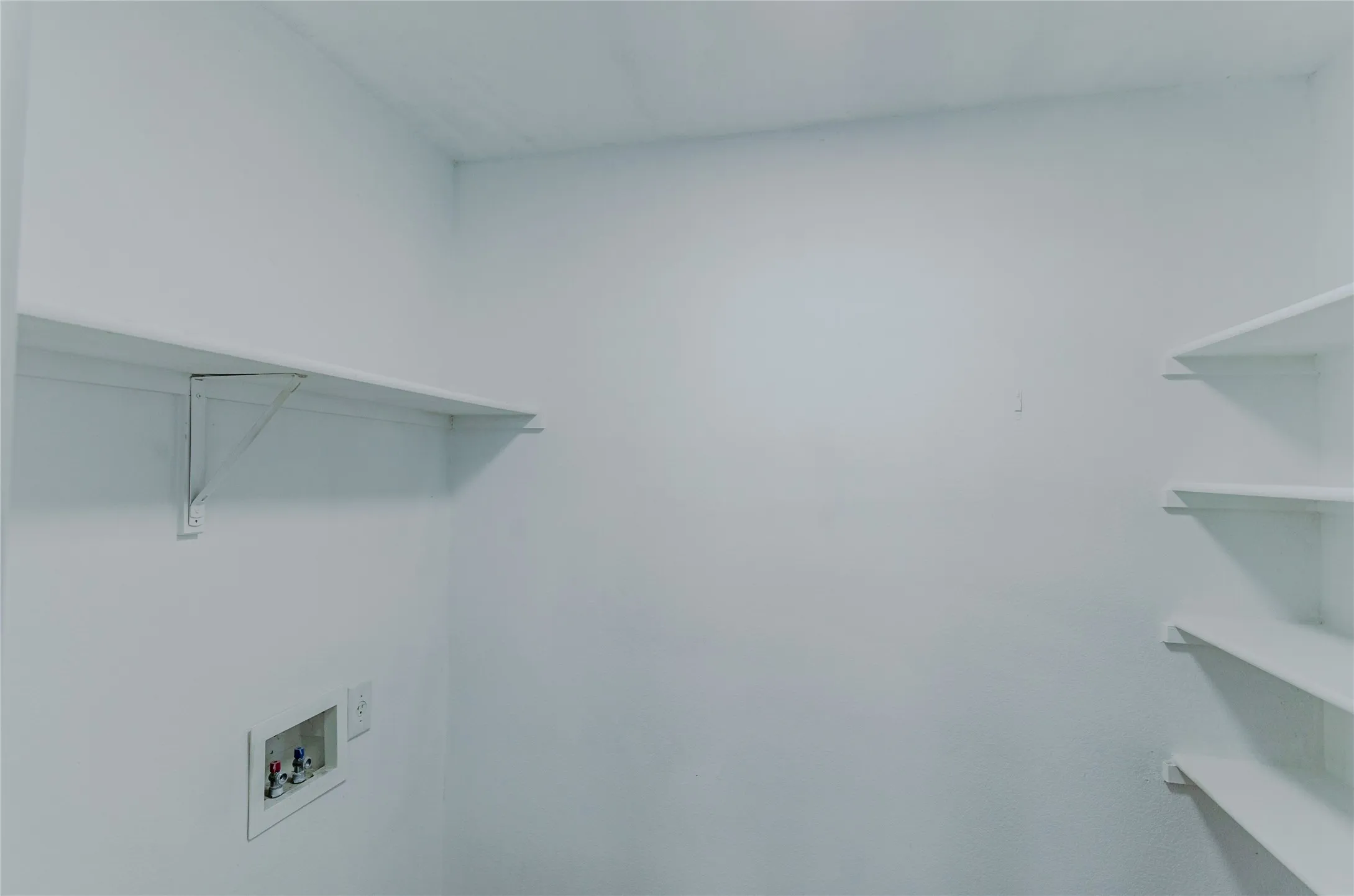 Laundry area featuring multiple storage shelves and integrated utility hookups