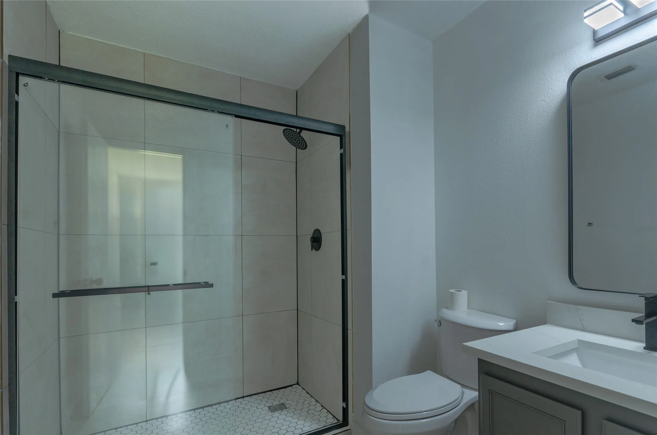 Bathroom featuring a glass-enclosed shower with subway tile surround and hexagonal tile flooring