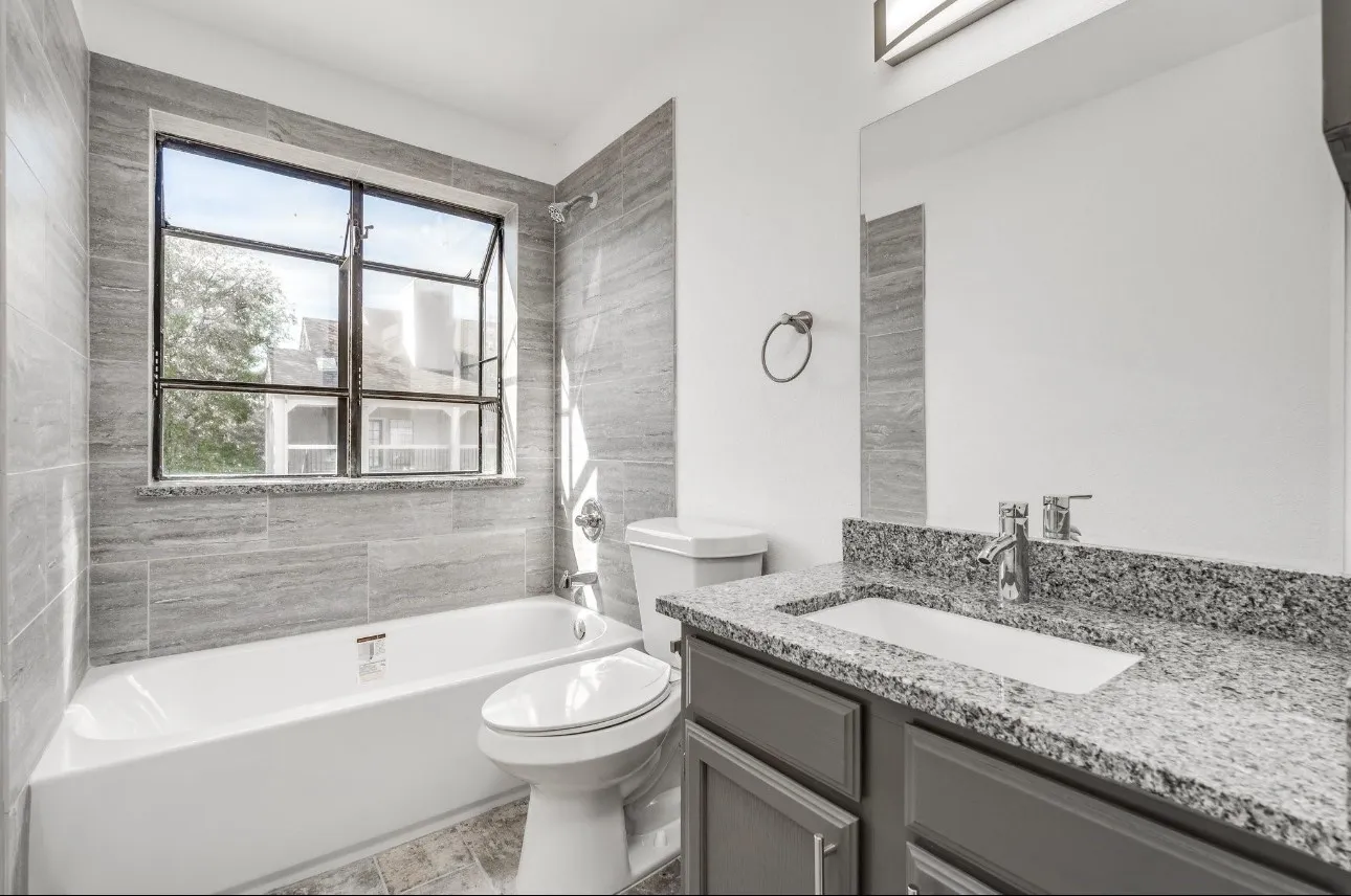 Full bathroom featuring a healthy amount of sunlight, toilet, tiled shower / bath combo, and vanity
