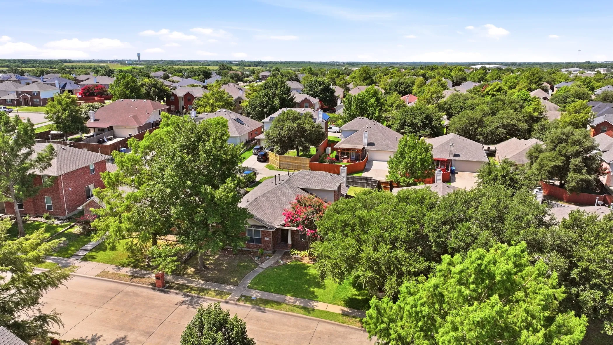 Residential neighborhood featuring a variety of single-story and two-story homes with brick and siding exteriors, mature trees, and individual fenced yards