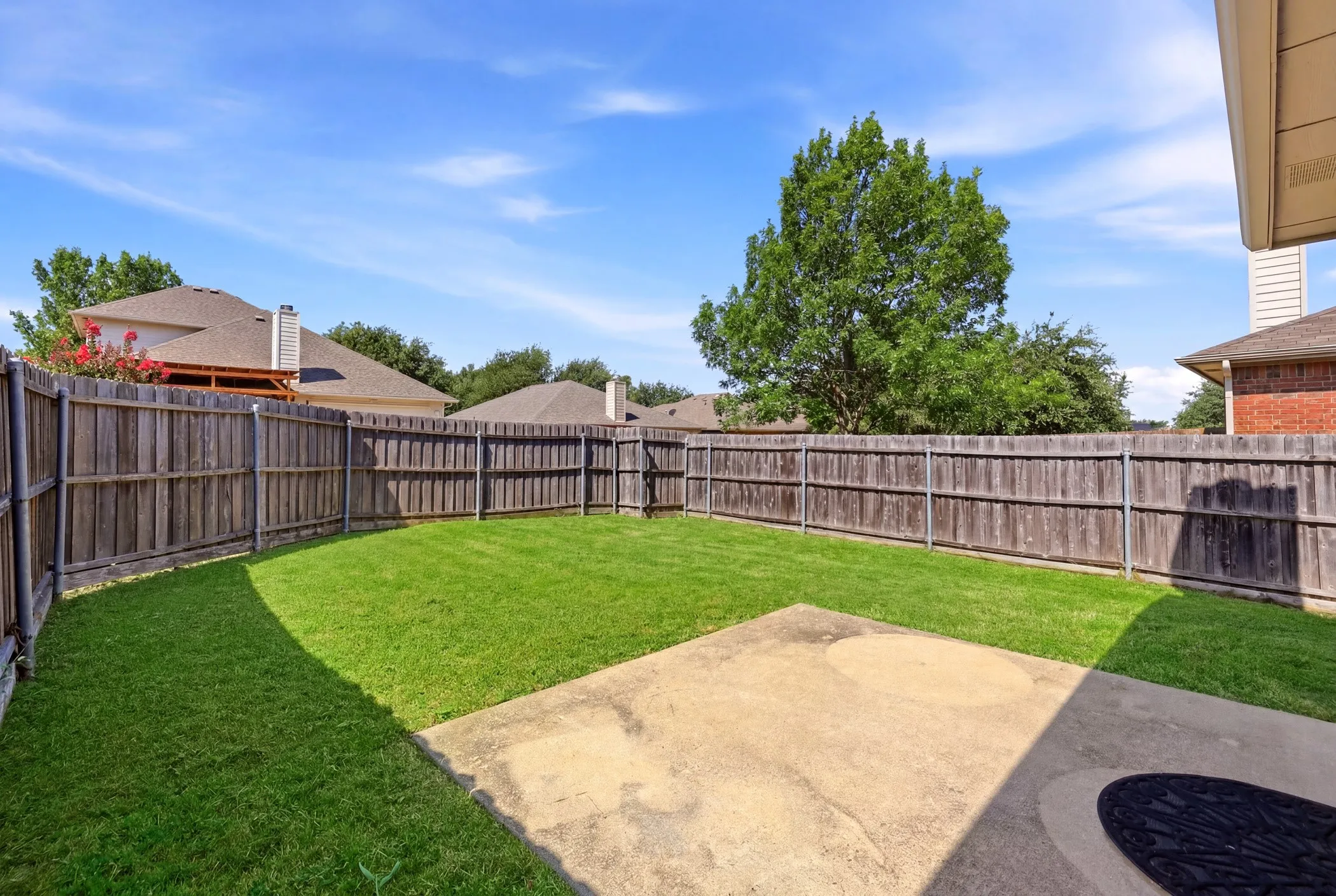 Private backyard featuring a well-maintained lawn, privacy fencing, and a concrete patio area