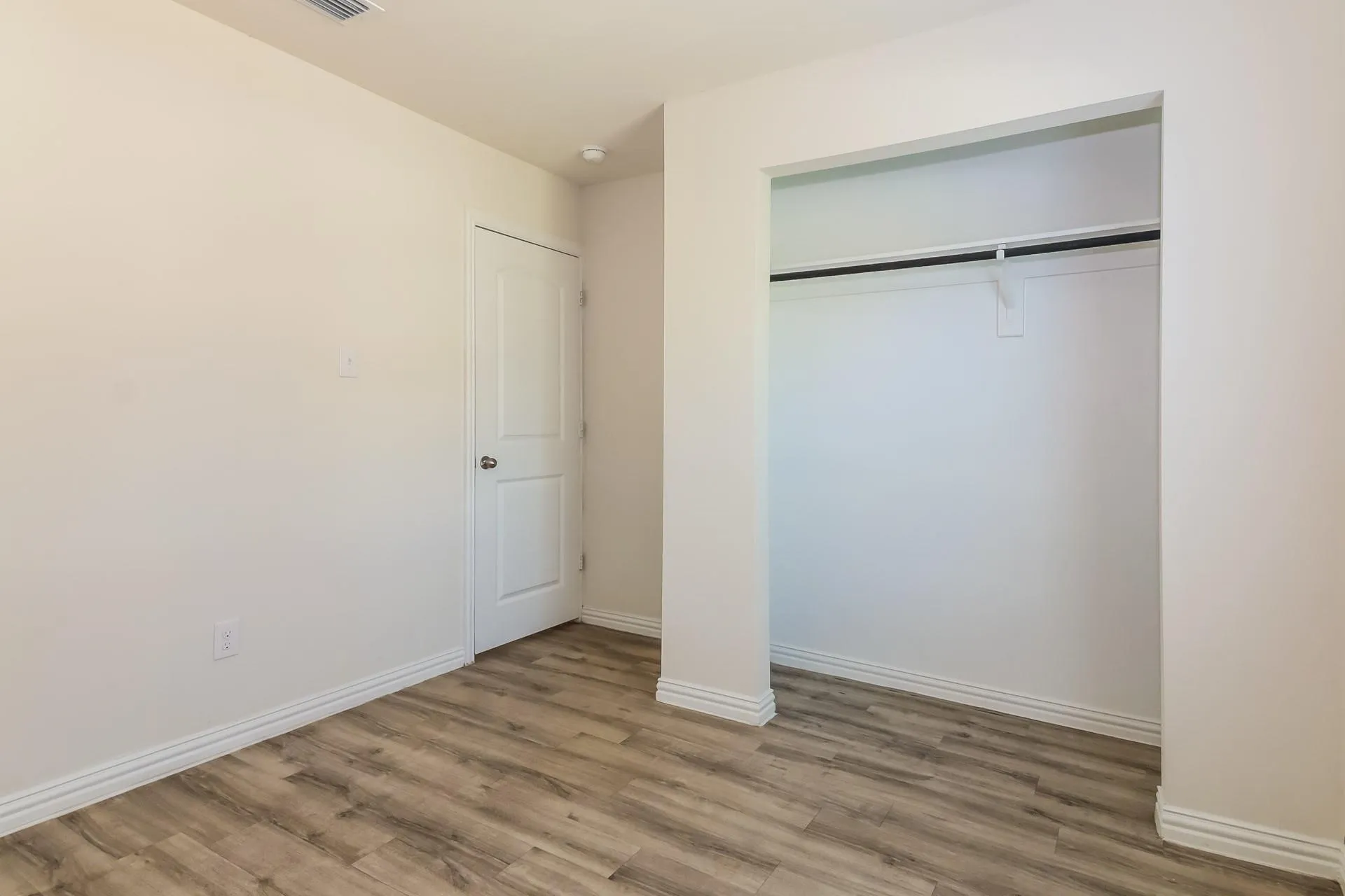 Room featuring wood-finish flooring, crisp white walls, and baseboard molding