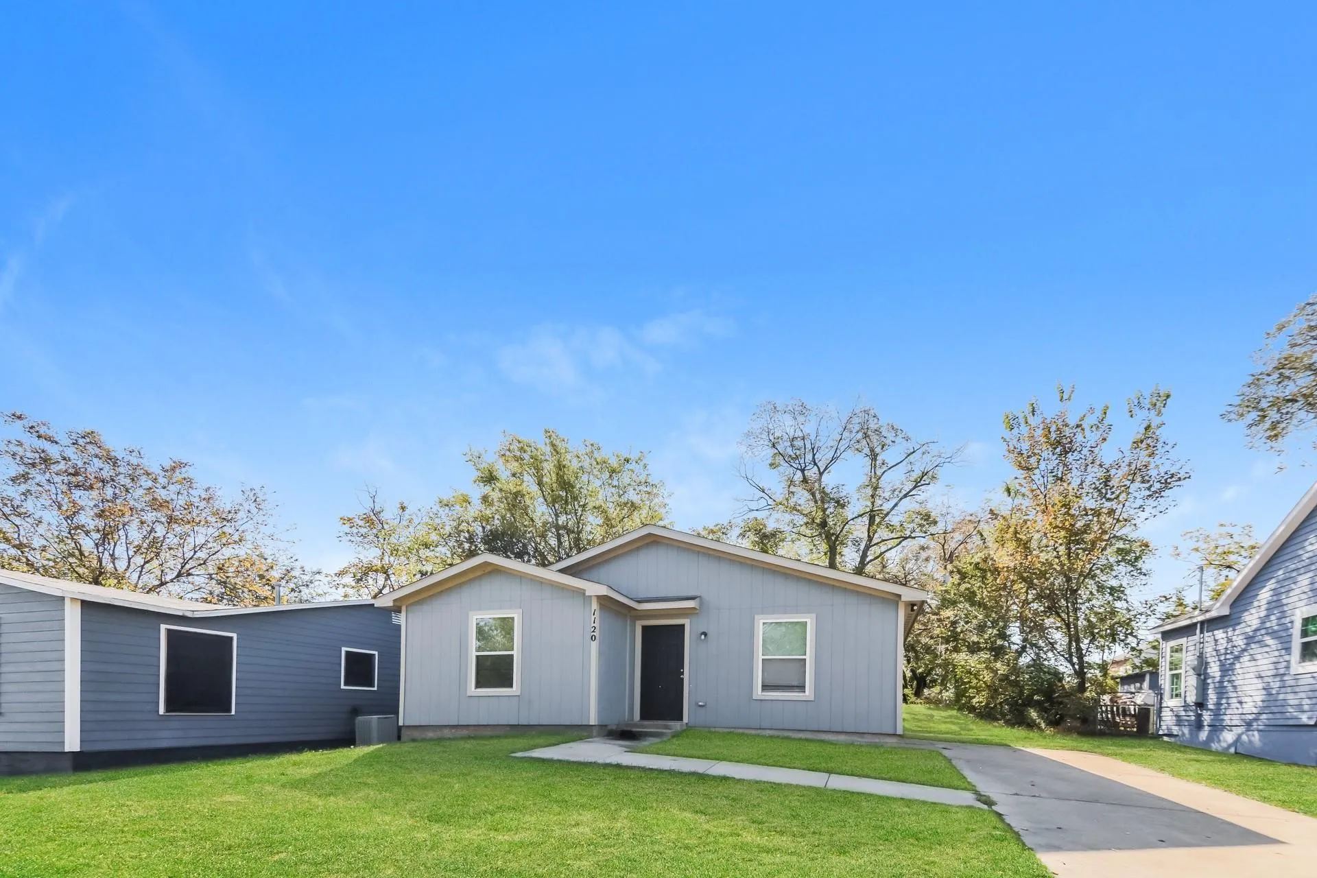 Light gray single-story residence featuring a dark entry door and white window trim