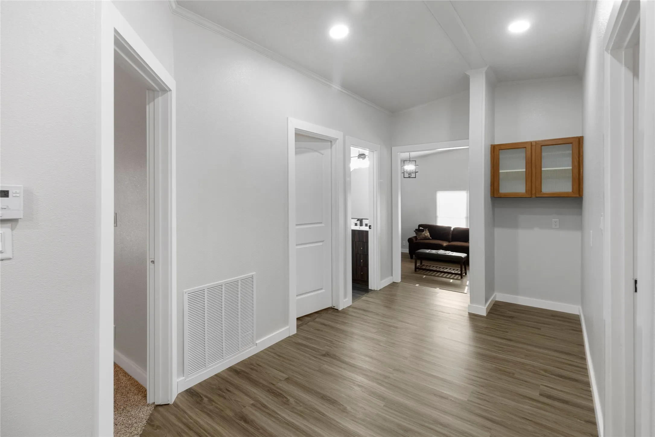Hallway in secondary bedrooms area and family room featuring wood-finish flooring, recessed lighting, and crisp white trim