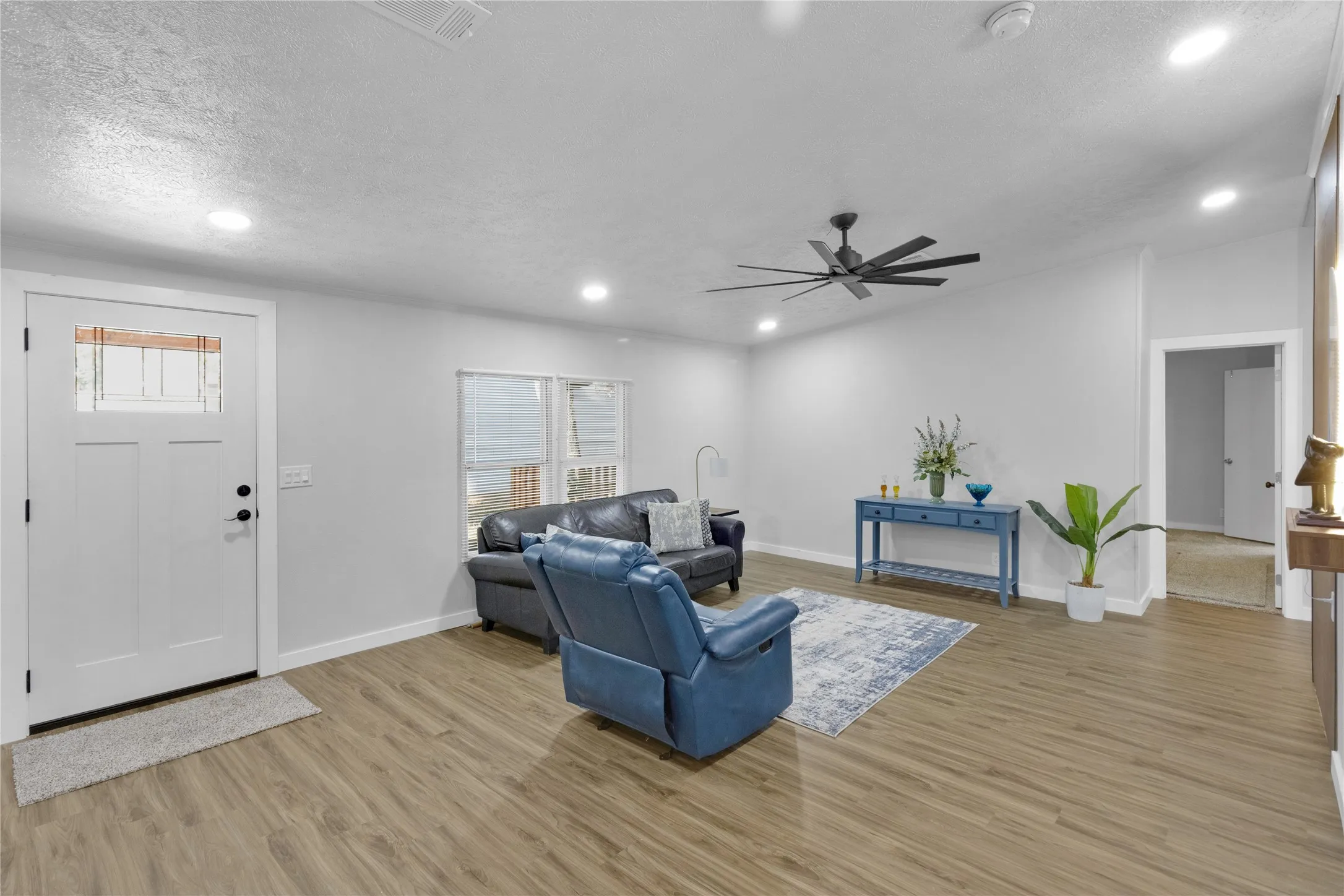 Bright living space featuring wood-finish flooring, recessed lighting, and a modern ceiling fan