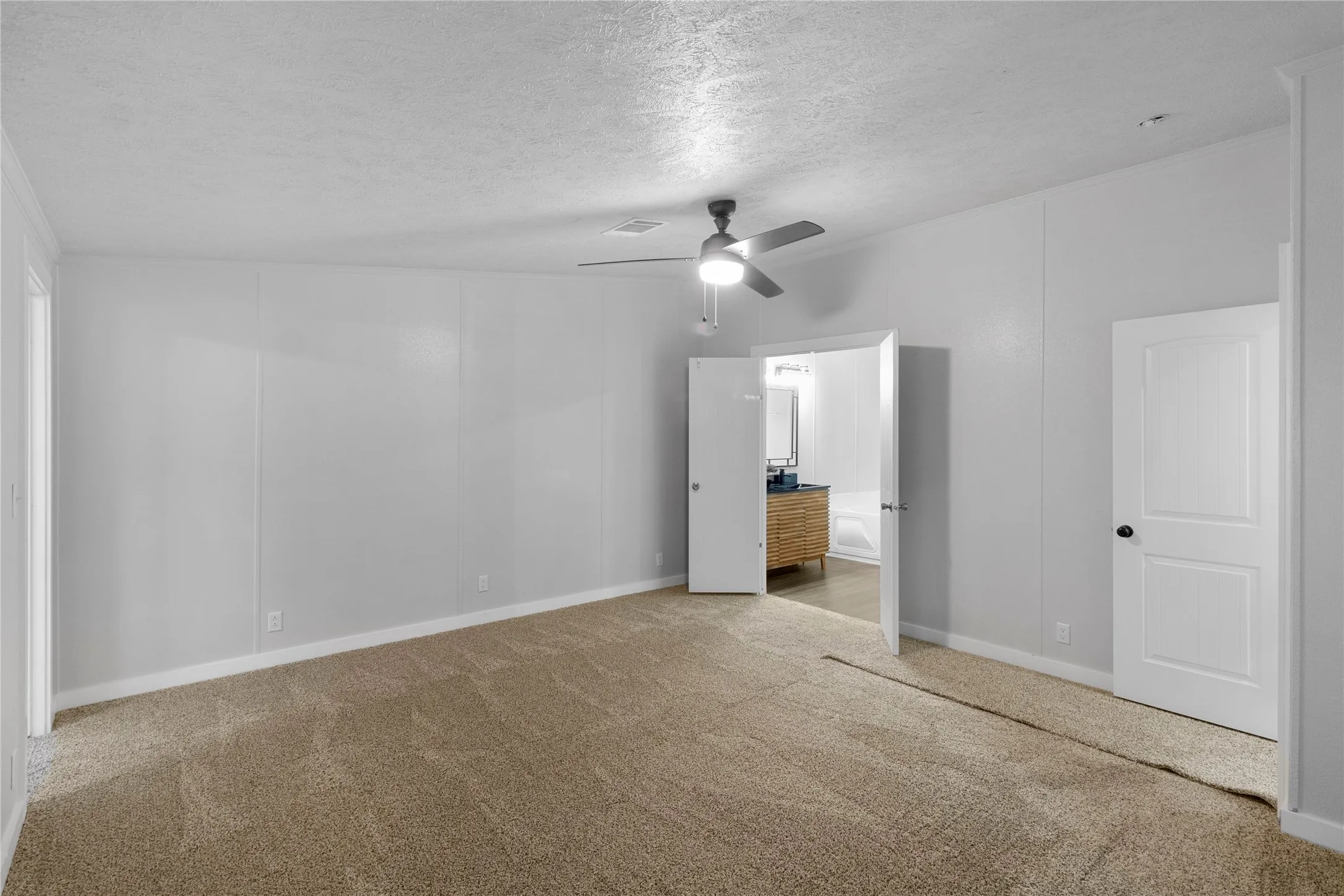 Spacious room with carpeted flooring, a ceiling fan with integrated lighting, and light-toned wall paneling