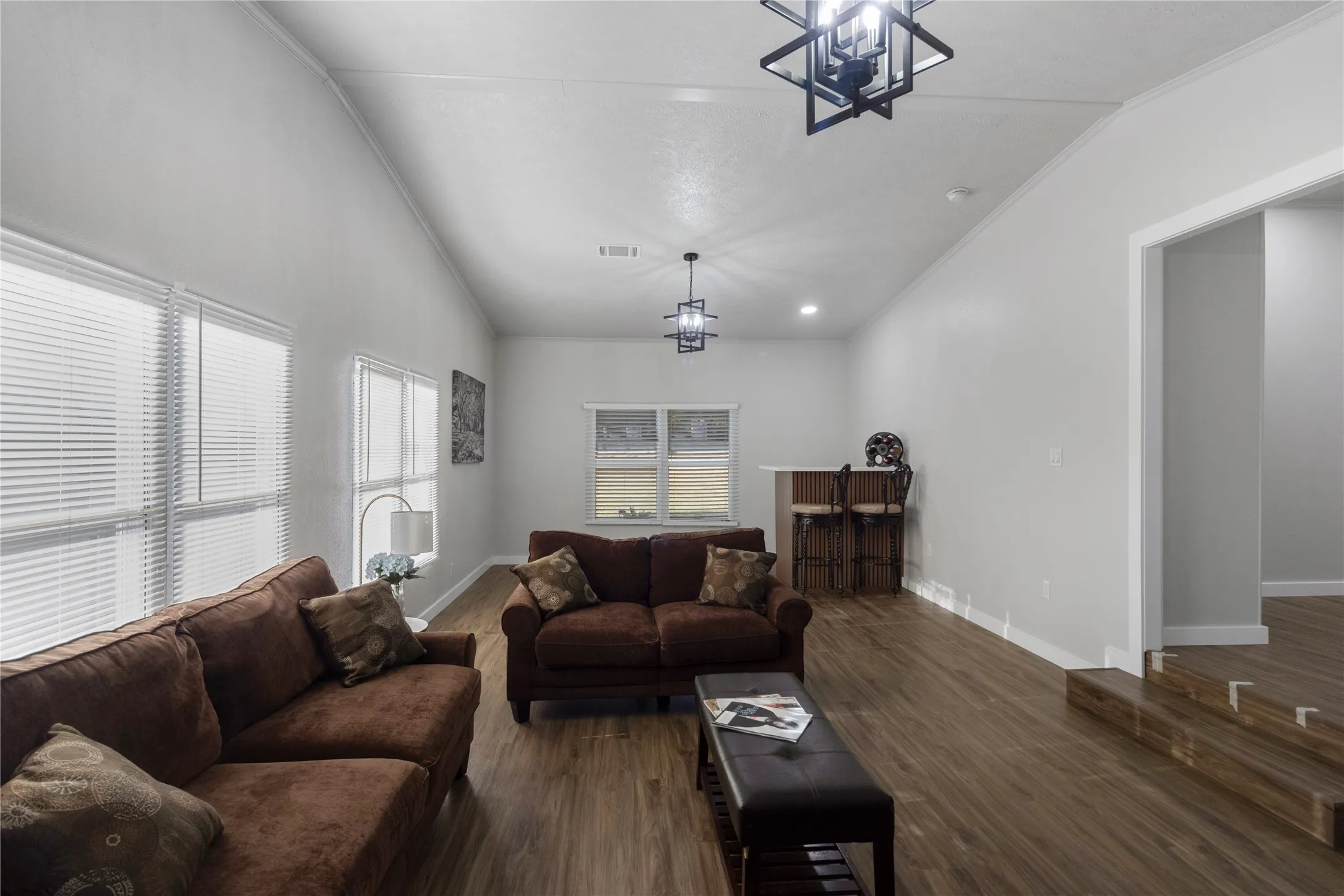 Spacious living area featuring wood-finish flooring, vaulted ceilings, and multiple windows