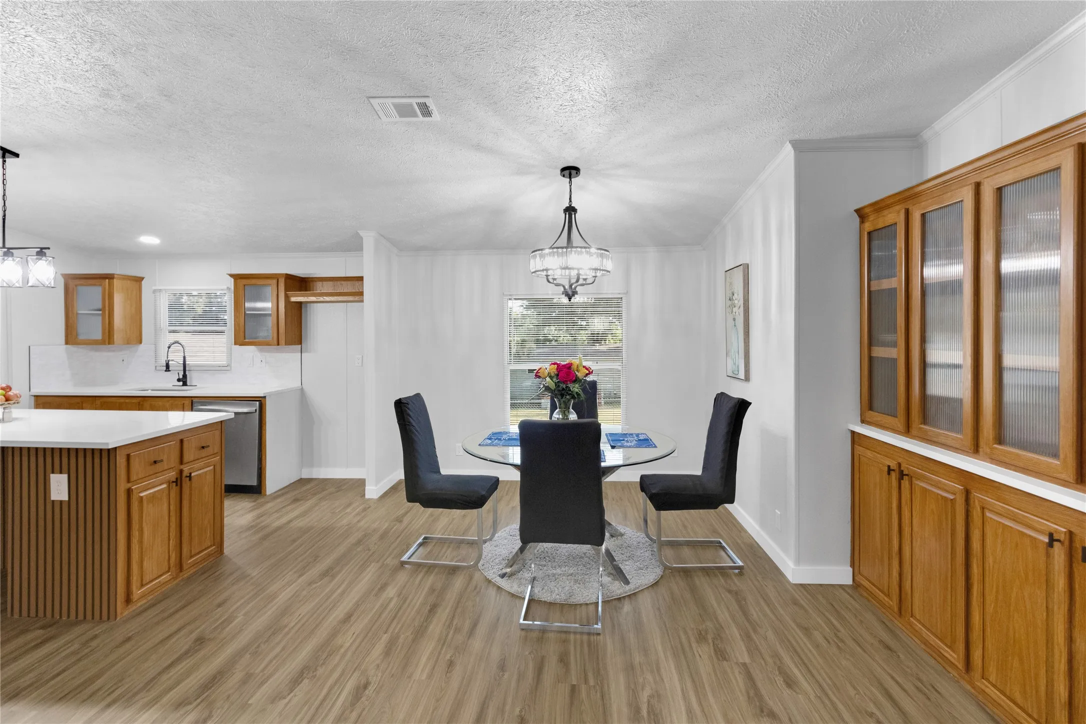 Open concept kitchen and dining area featuring wood-finish flooring, white walls, and a recessed ceiling light