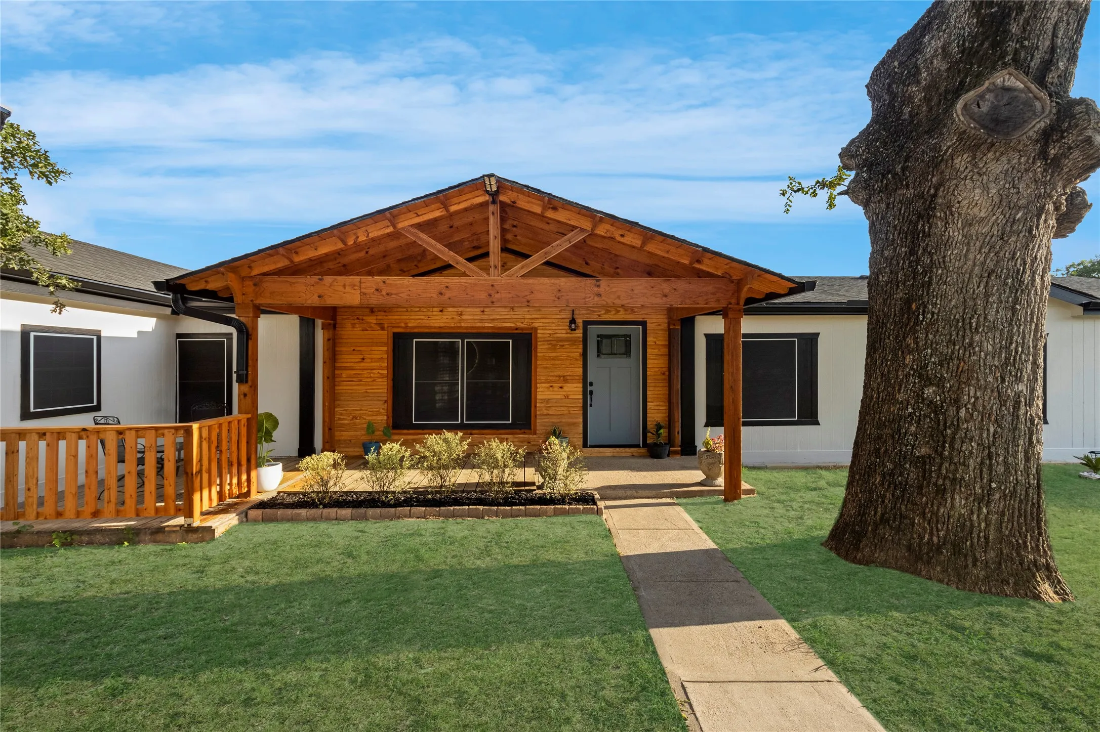 Front exterior featuring a prominent wood-clad entryway with an exposed beam porch, light blue entry door, and dark window trim