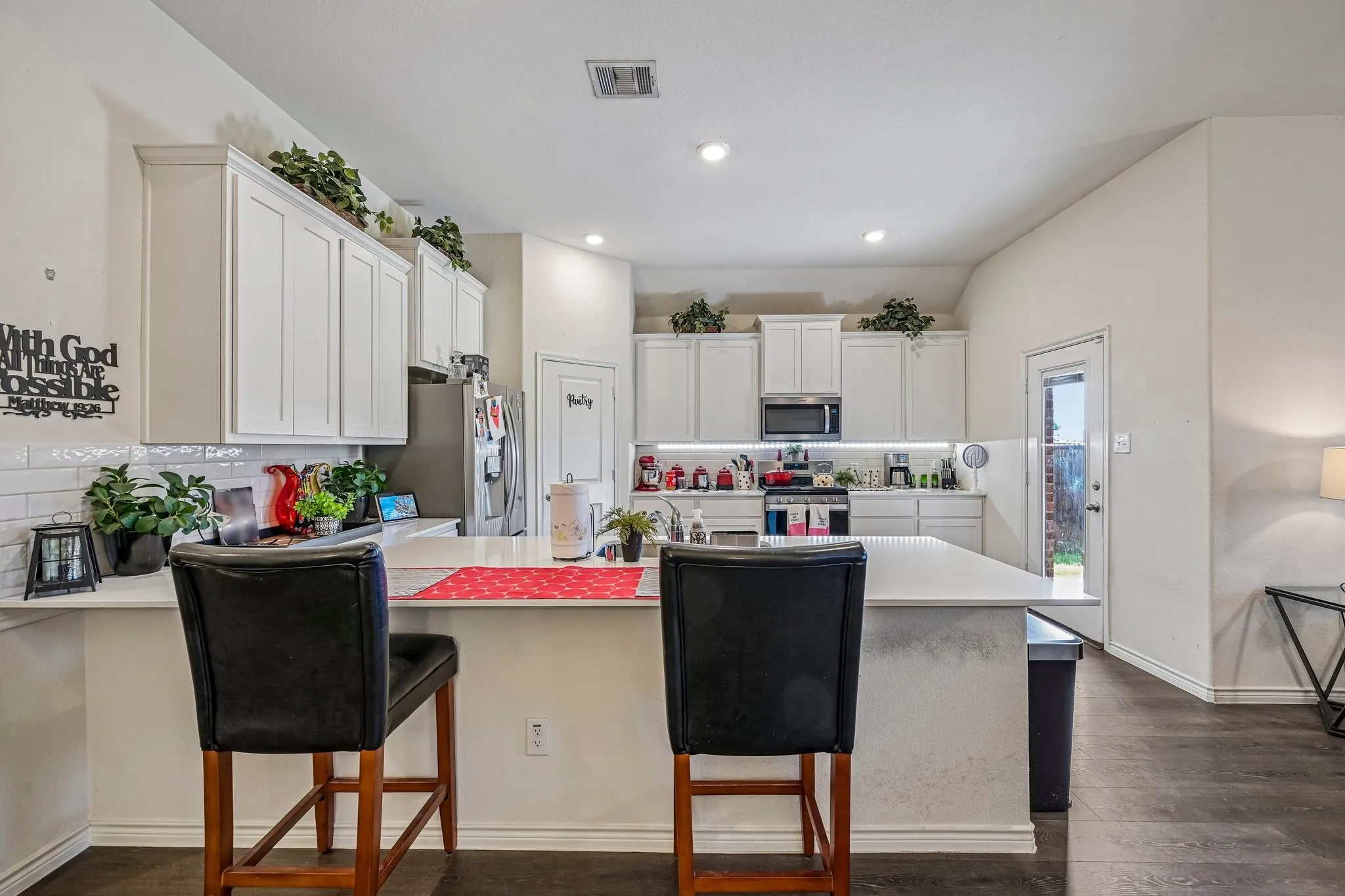 Kitchen featuring white shaker cabinetry, white subway tile backsplash, white countertops, stainless steel appliances, and dark wood-finish flooring