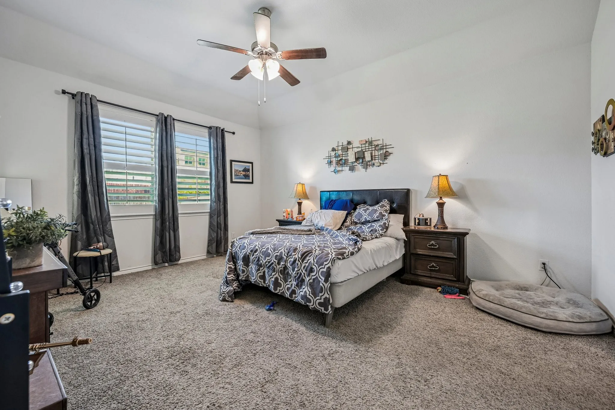 Carpeted room featuring a ceiling fan with integrated lighting, white walls, and multiple windows with blinds and curtains