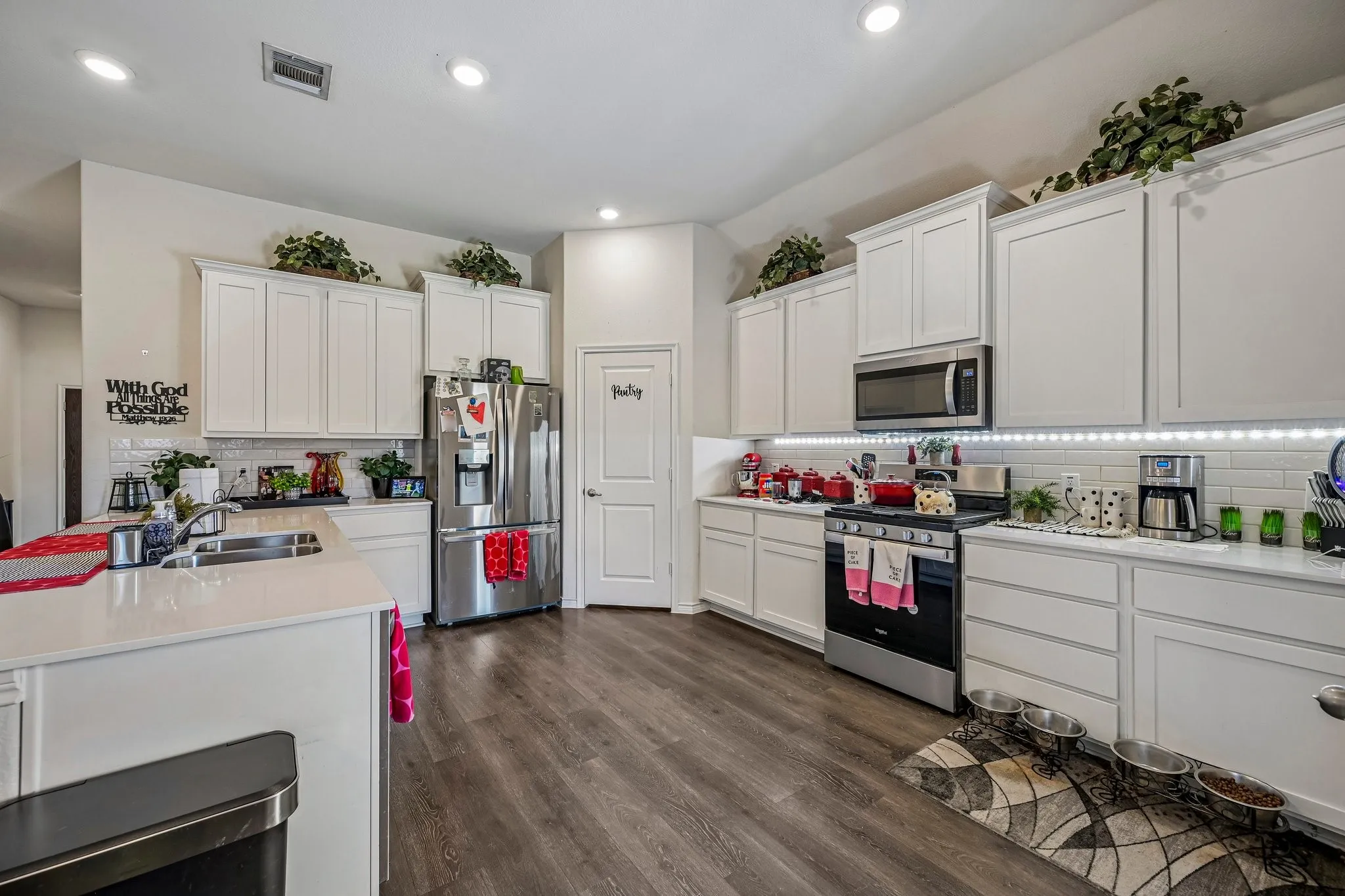 Modern kitchen featuring white shaker cabinetry, stainless steel appliances, a subway tile backsplash, recessed lighting, and wood-finish flooring