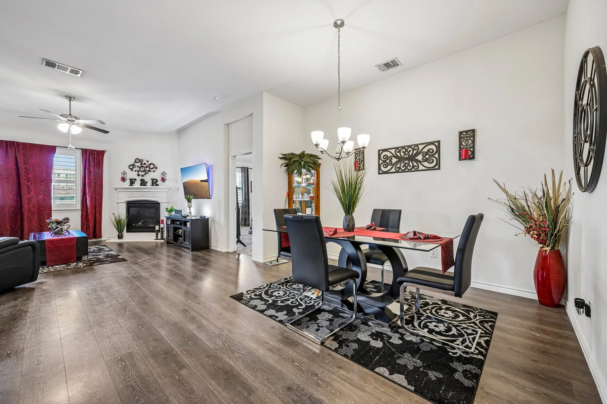 Spacious living area featuring wood-finish flooring, a fireplace with a white mantel, and a ceiling fan