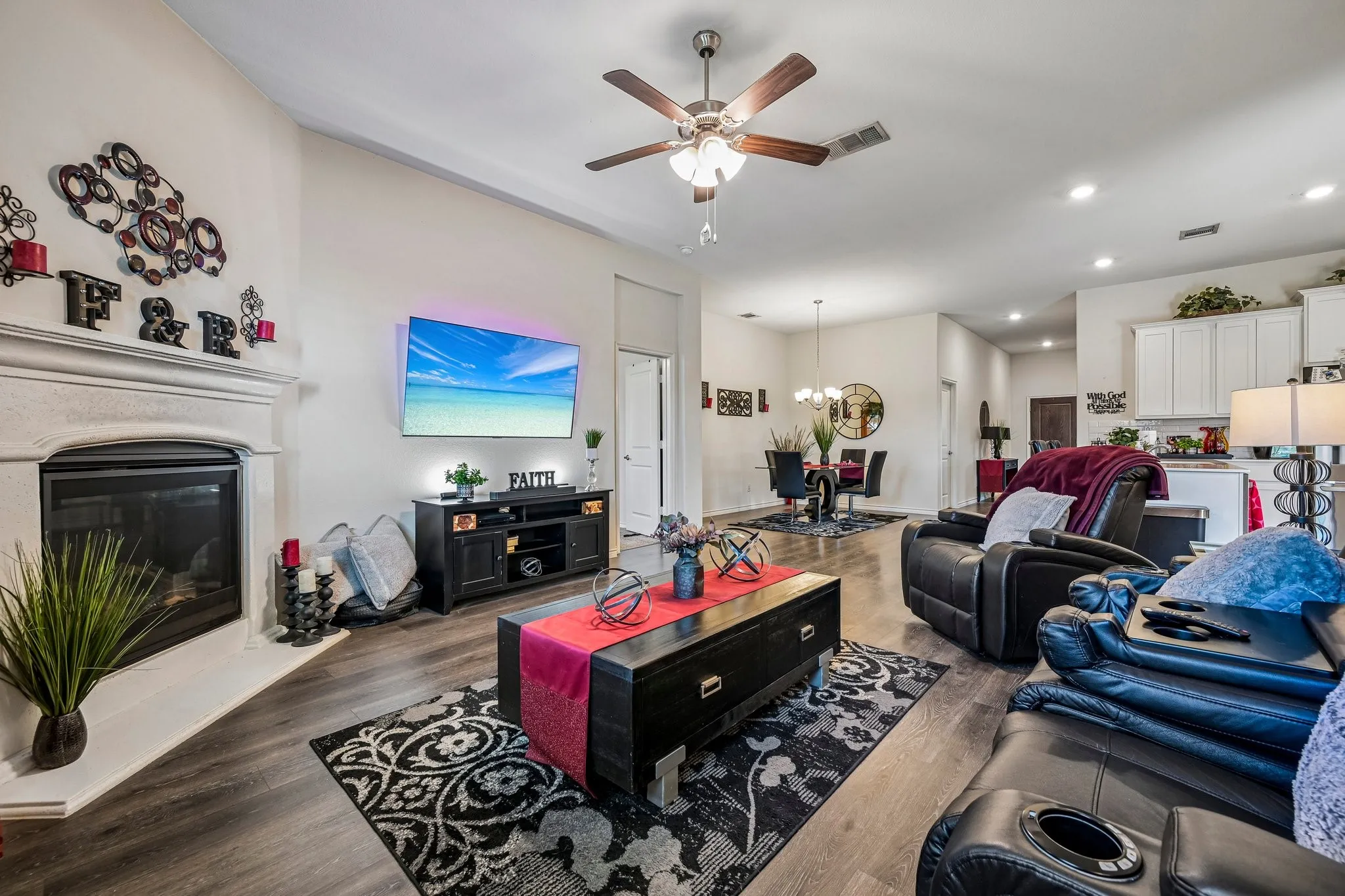 Living area featuring wood-finish flooring, a fireplace with a detailed mantel, and a ceiling fan