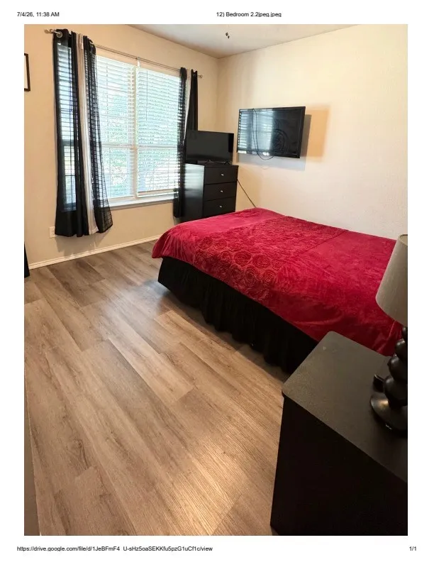 Bedroom featuring wood-finish flooring, a double window with horizontal blinds, and neutral wall paint