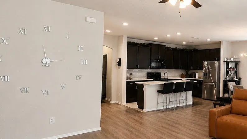 Open-concept kitchen featuring dark wood cabinetry, light countertops, and a subway tile backsplash