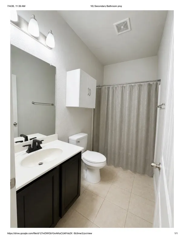 Bathroom featuring a dark wood-finish vanity with an integrated sink, white countertop, and matte black faucet