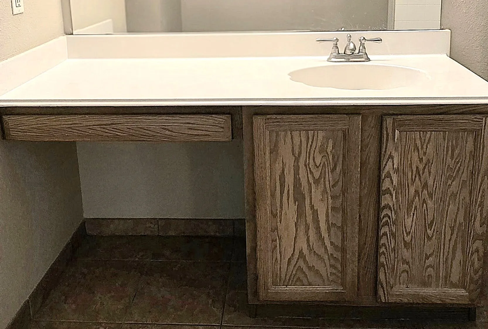 Vanity with a white countertop, an integrated sink, a dual-handle faucet, and wood-finish cabinetry