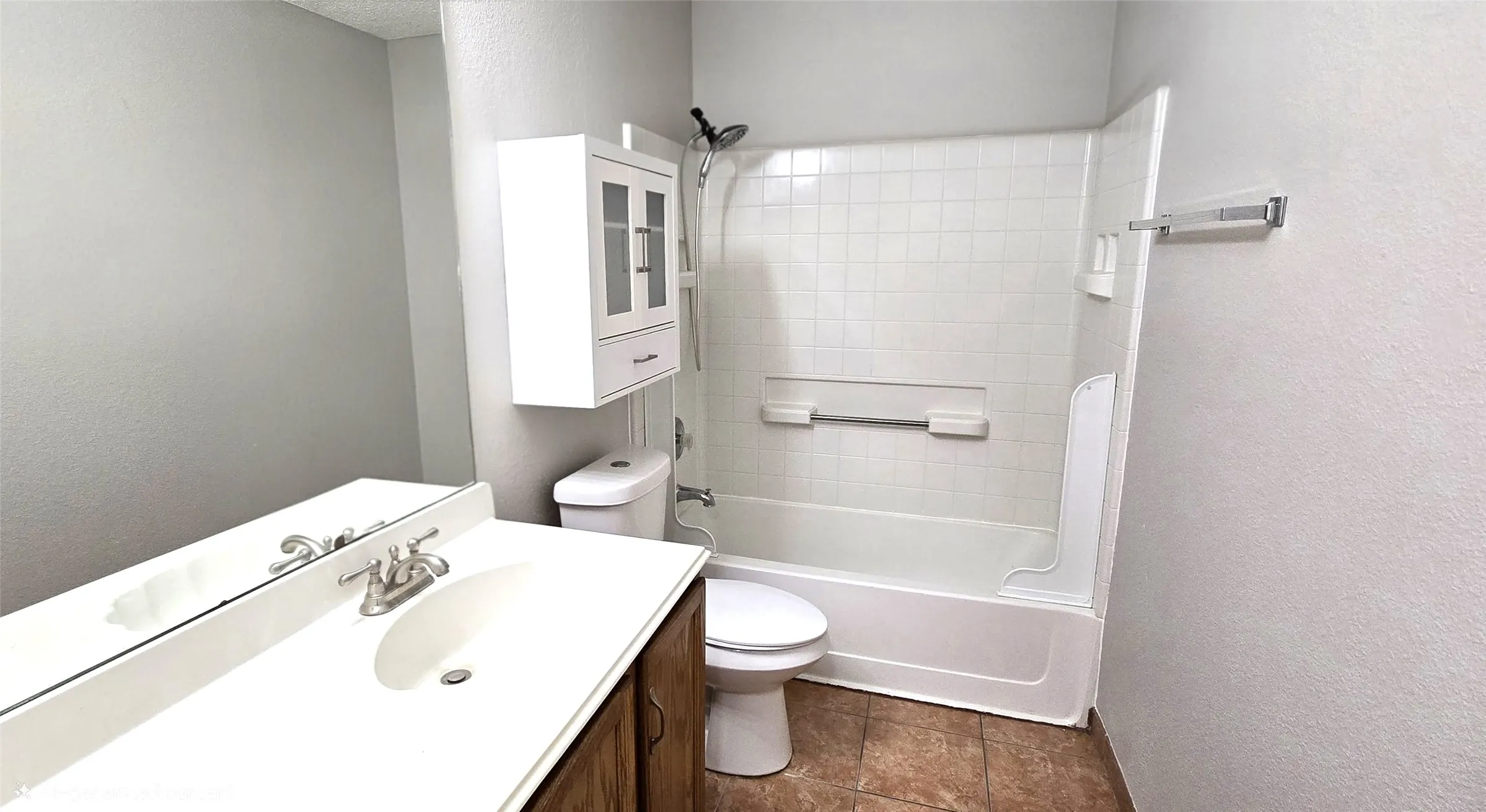 Bathroom featuring a wood-finish vanity, integrated sink, and brushed nickel fixtures