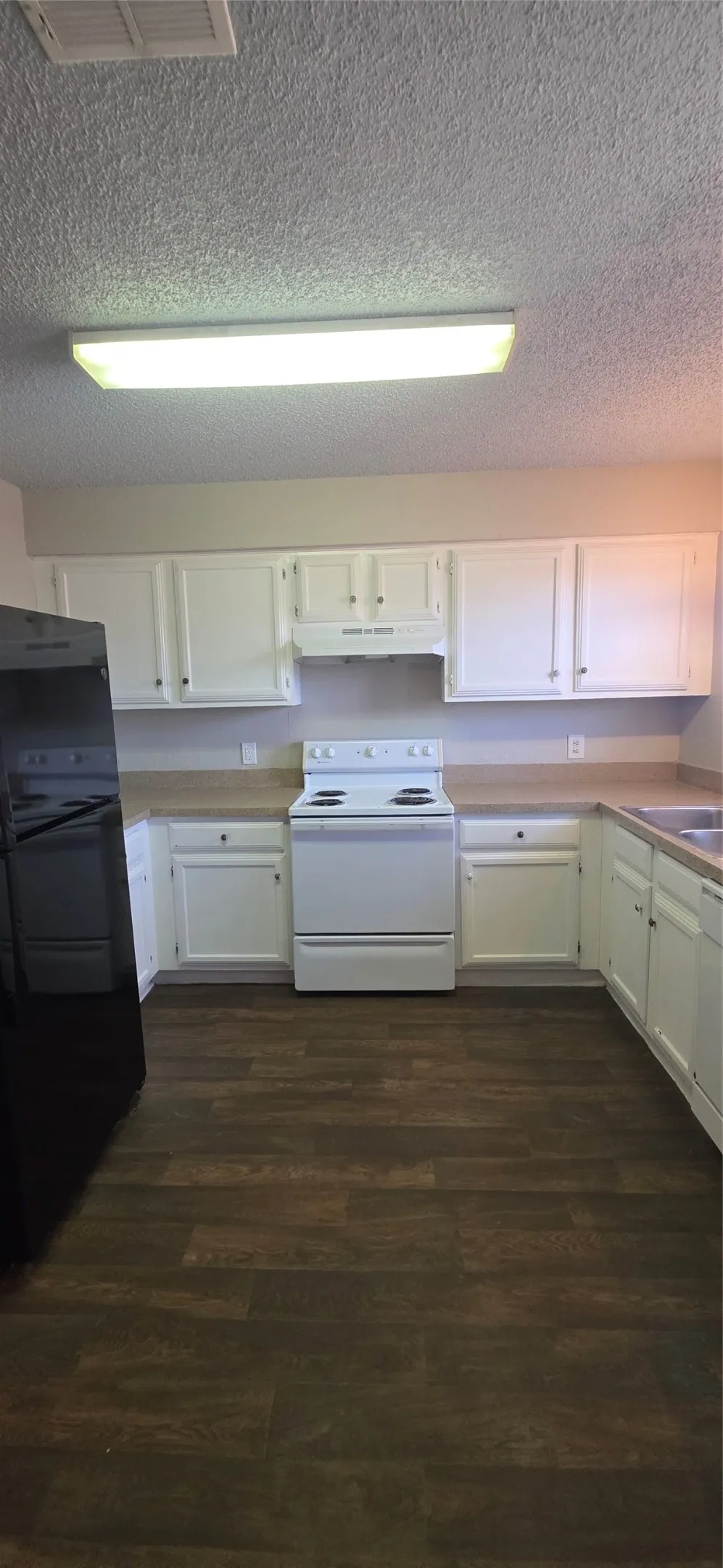 Kitchen featuring wood-finish flooring, white cabinetry, a white electric range, and a black refrigerator